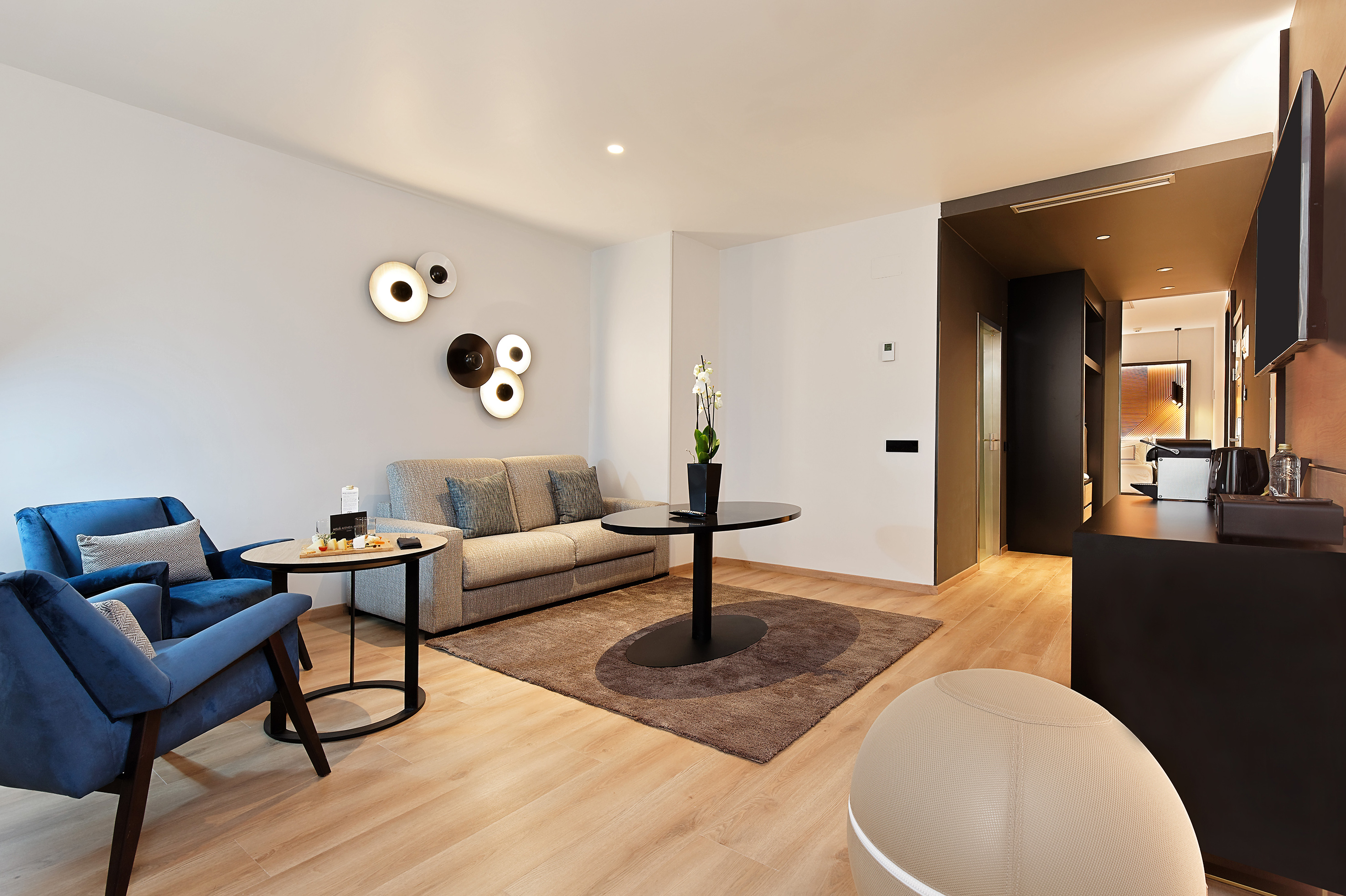 Comfortable modern hotel suite lounge with blue armchairs and sofa.