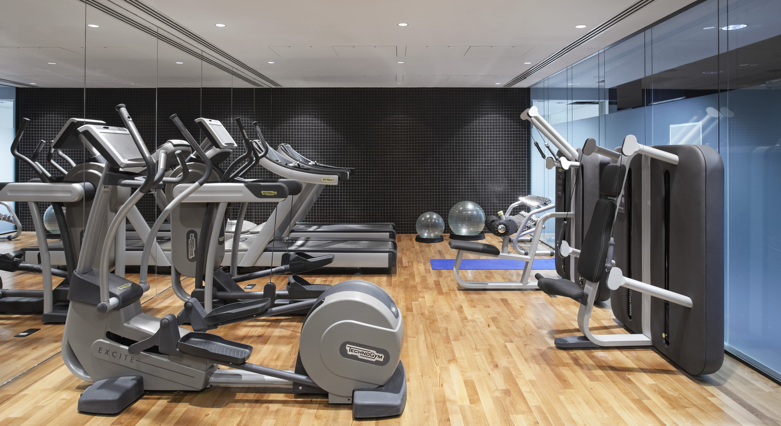 Modern gym with Technogym ellipticals, treadmills, and weight machines.
