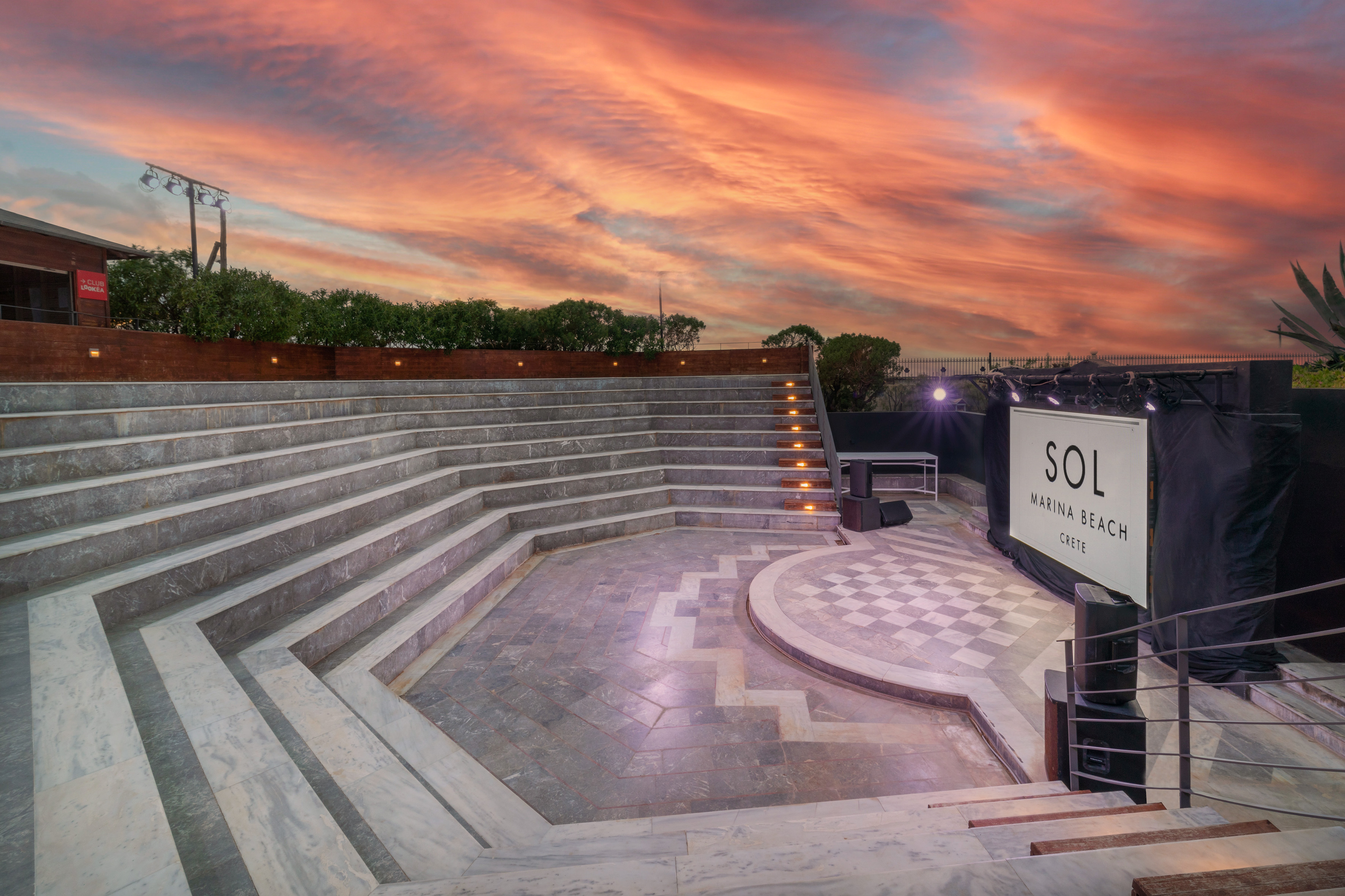 Outdoor marble amphitheater with SOL Marina Beach Crete stage at sunset.