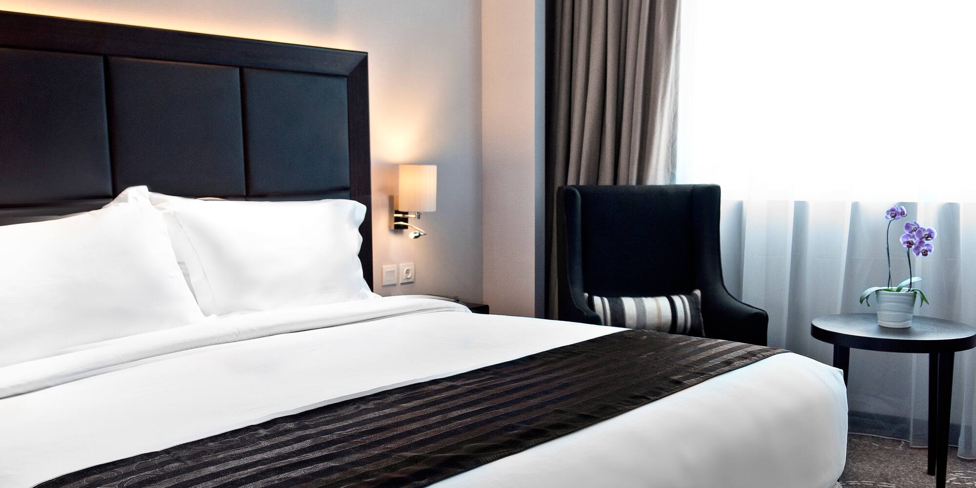 a bed with a black headboard and a chair in a room