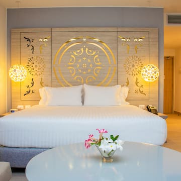 a bed with white sheets and a round table with flowers in a room
