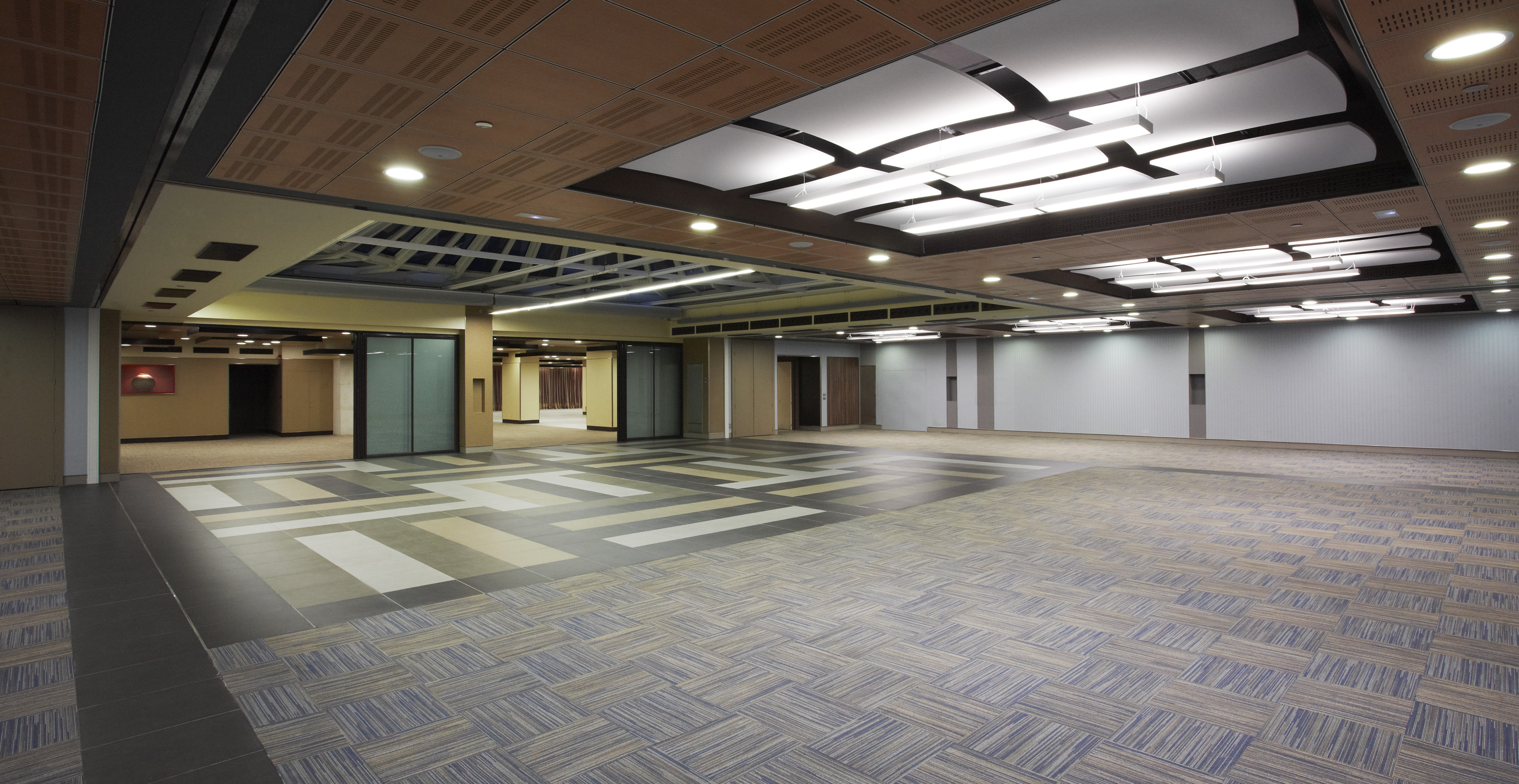 Modern empty conference hall with patterned floor and acoustic ceiling.