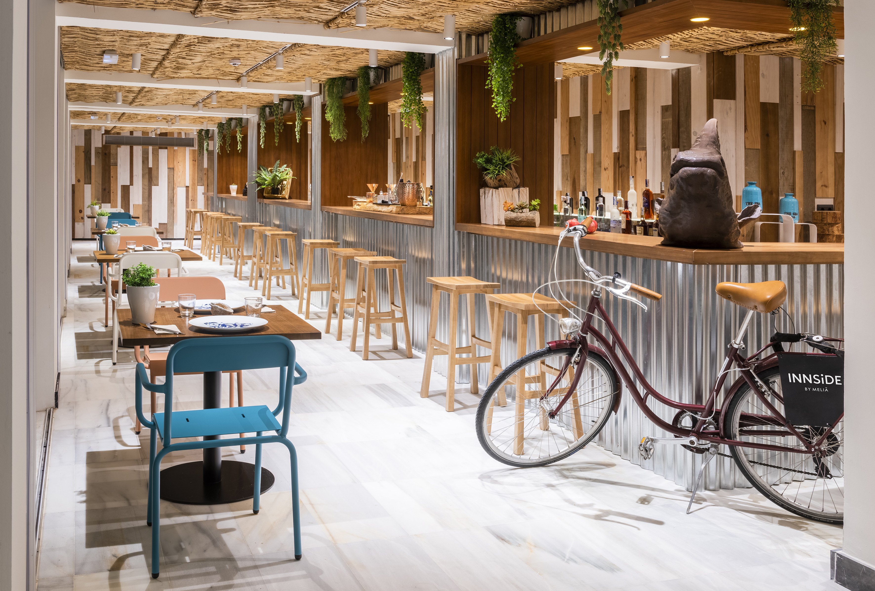 Innside by Meliá restaurant bar, thatched roof, wood, metal, plants, bicycle.