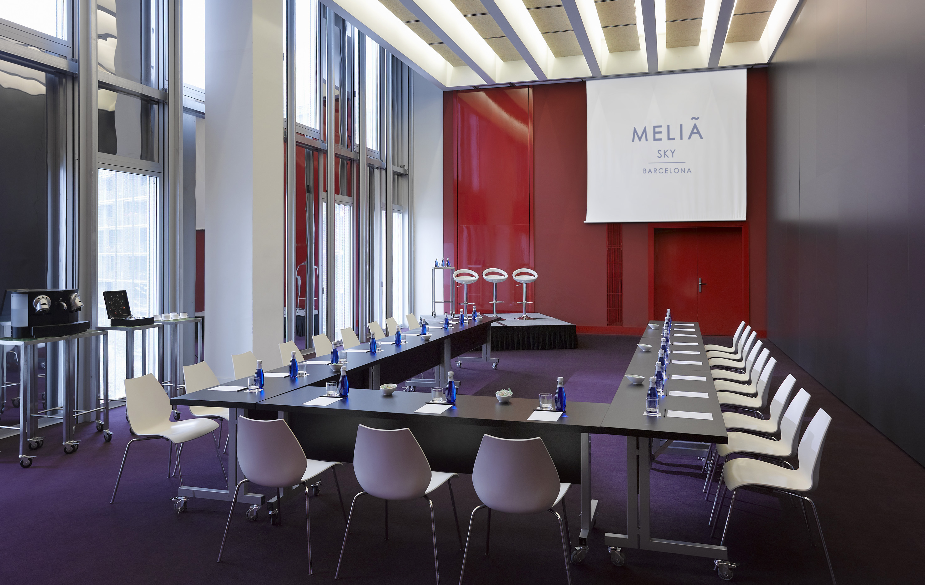 Meliã Sky Barcelona conference room, U-shaped setup, red wall, large windows.