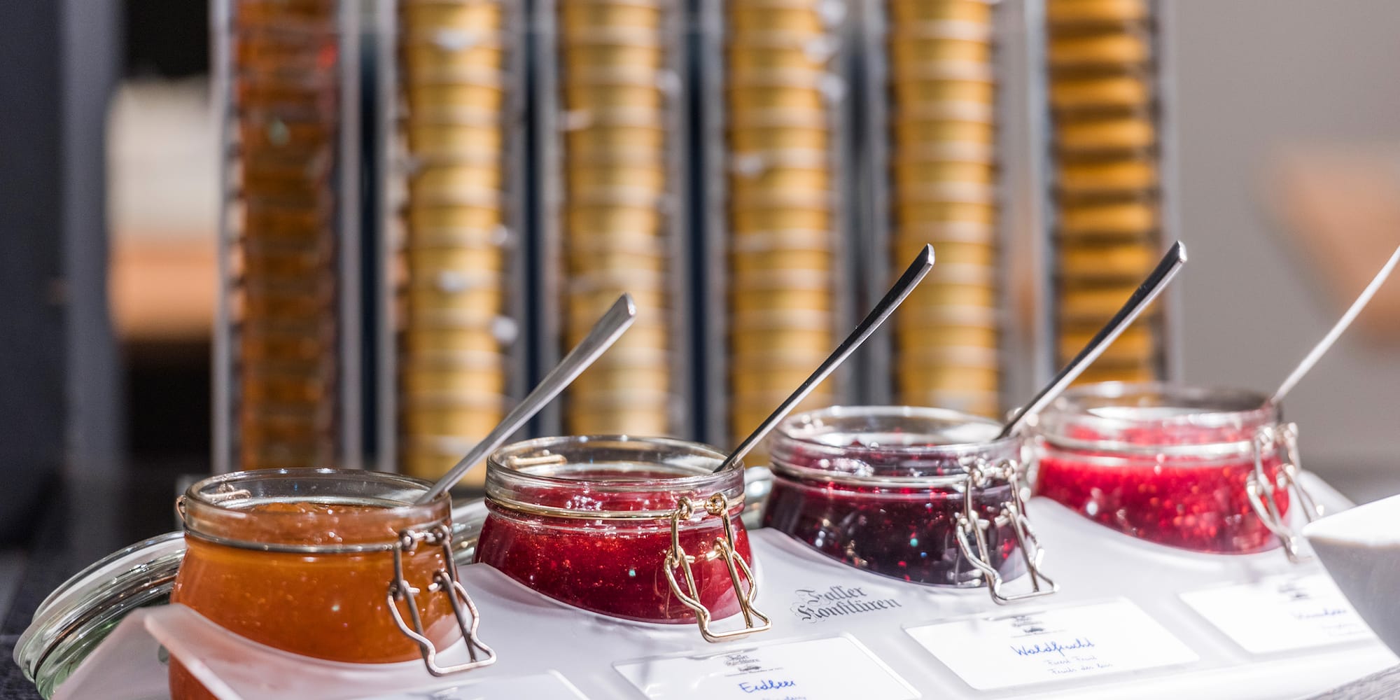 jars of jam in a container with spoons