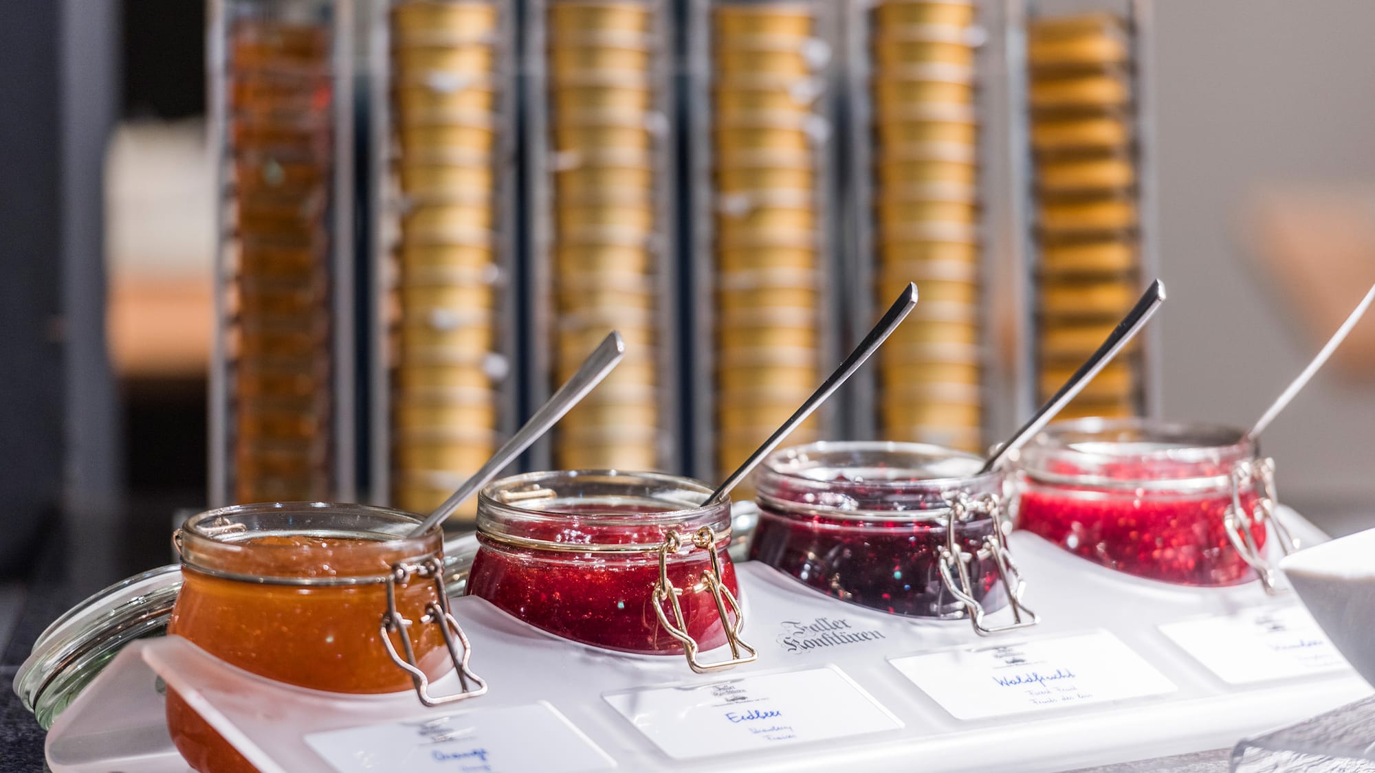 jars of jam in a container with spoons
