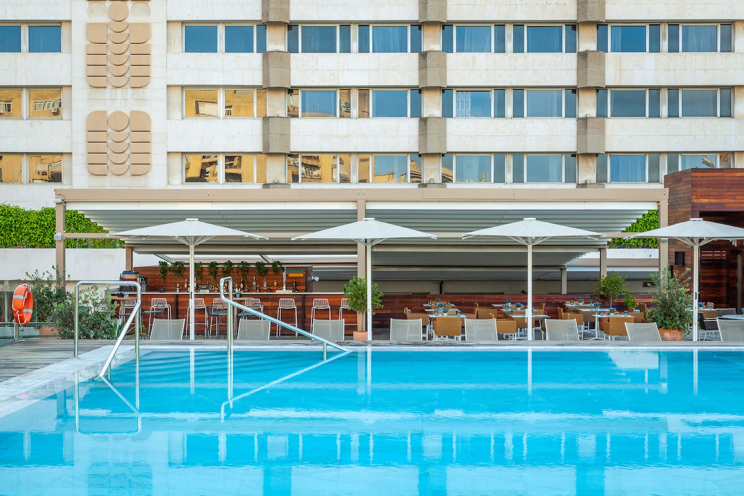 a pool with umbrellas and chairs in front of a building