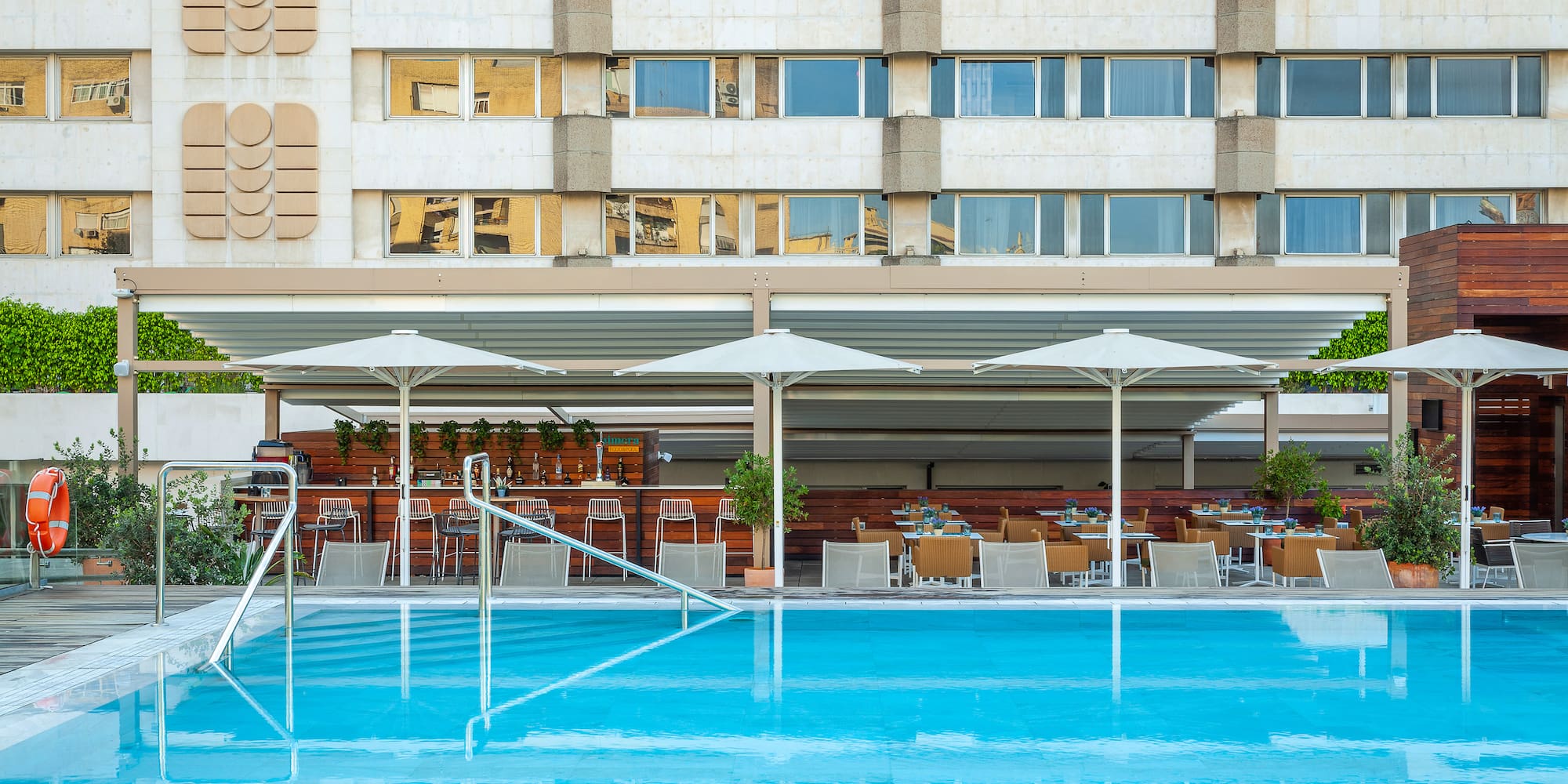 a pool with umbrellas and chairs in front of a building