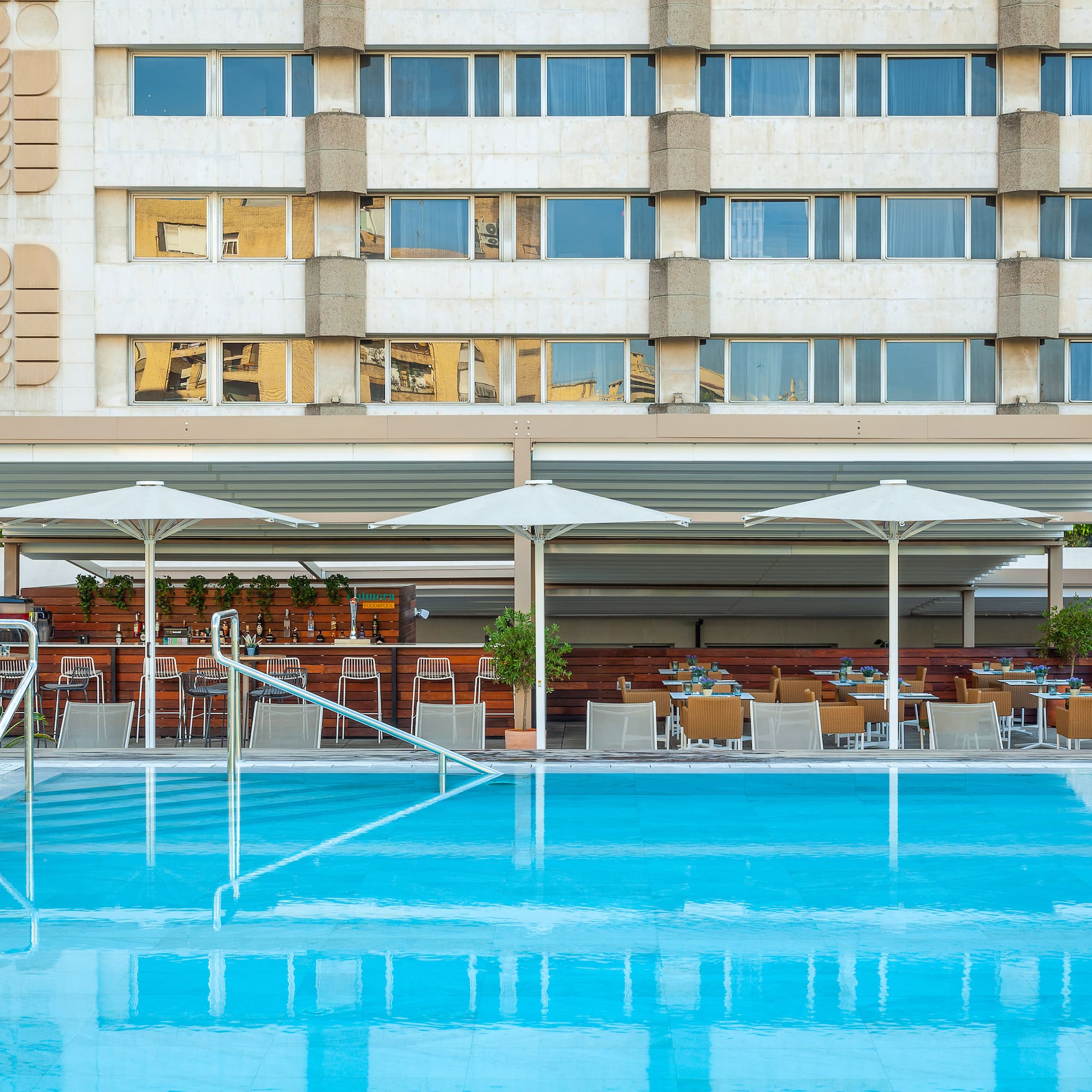 a pool with umbrellas and chairs in front of a building