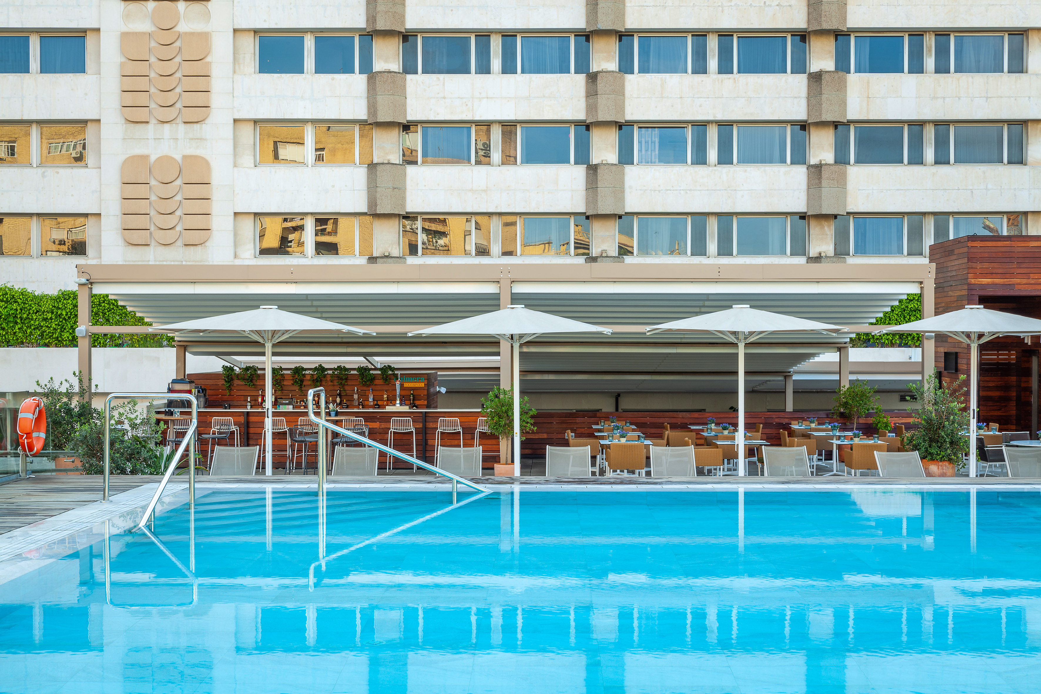 a pool with umbrellas and chairs in front of a building