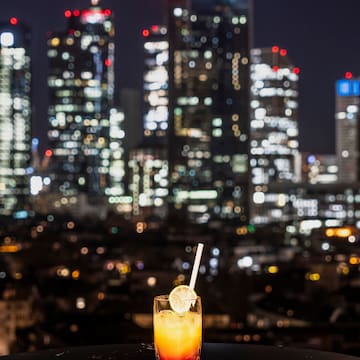 a glass of drink with a straw in front of a city skyline