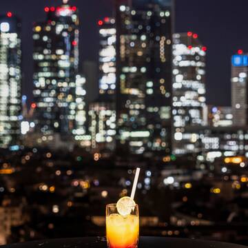 een glas drinken met een rietje voor een skyline van een stad