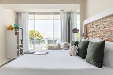 a bed with pillows and a bookcase in a room with a view of the water