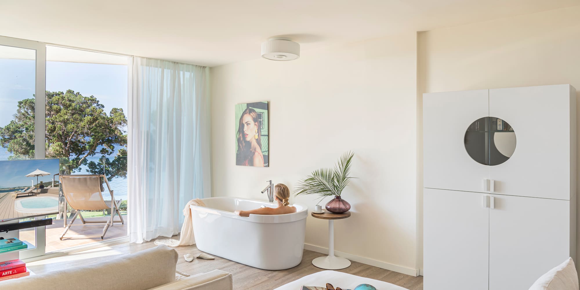 a woman in a bathtub in a room with a white couch and a white bed