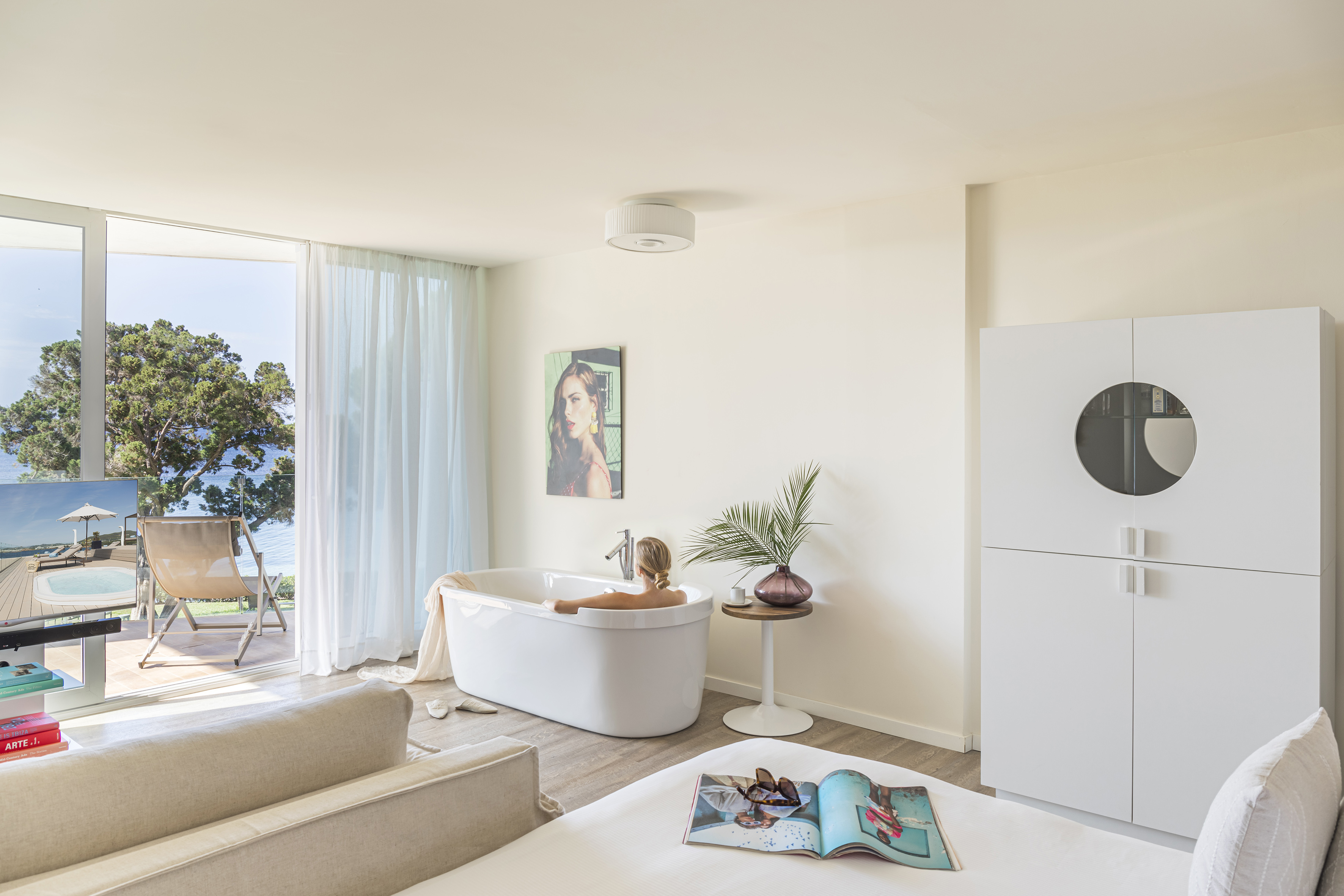 a woman in a bathtub in a room with a white couch and a white bed