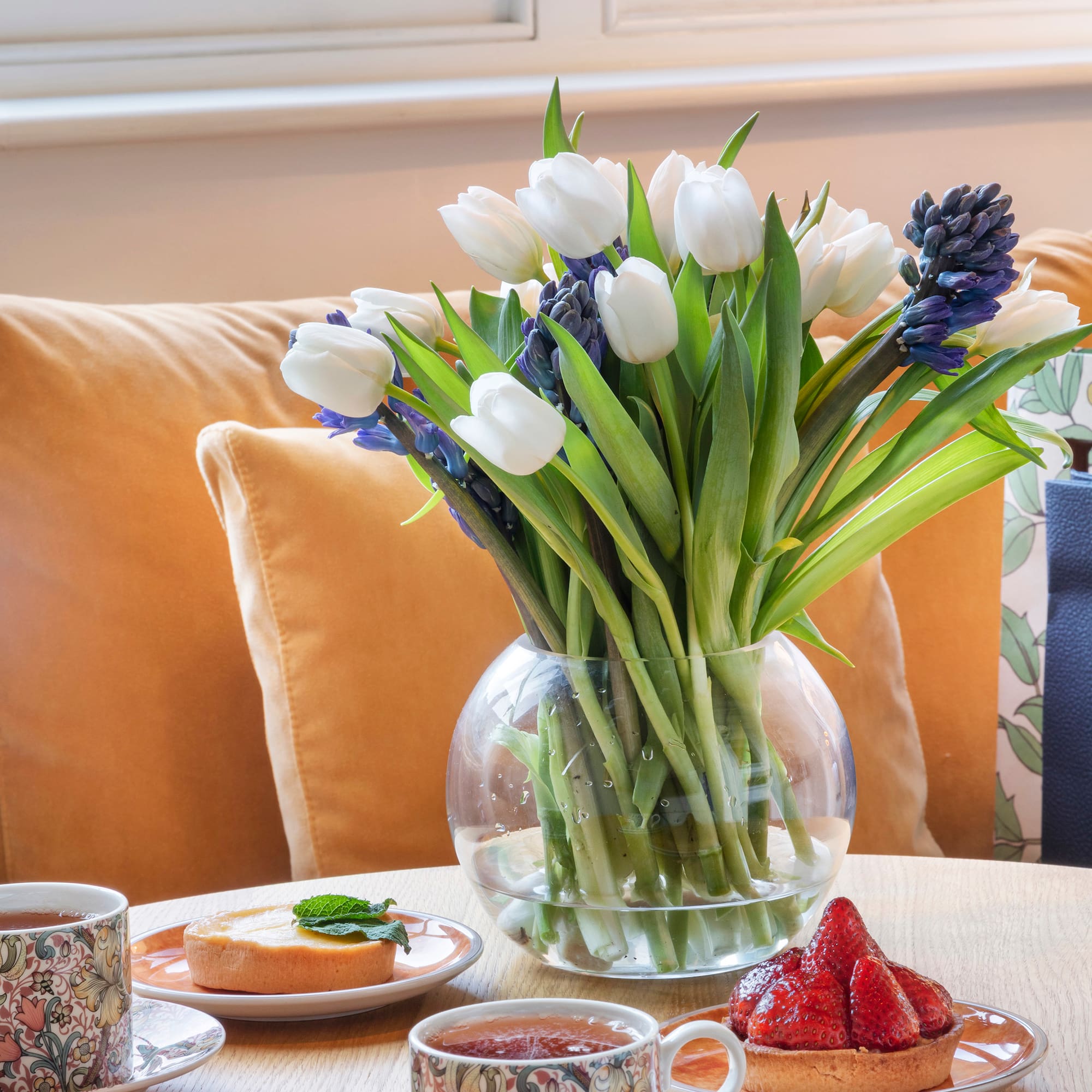 a vase of flowers and desserts on a table