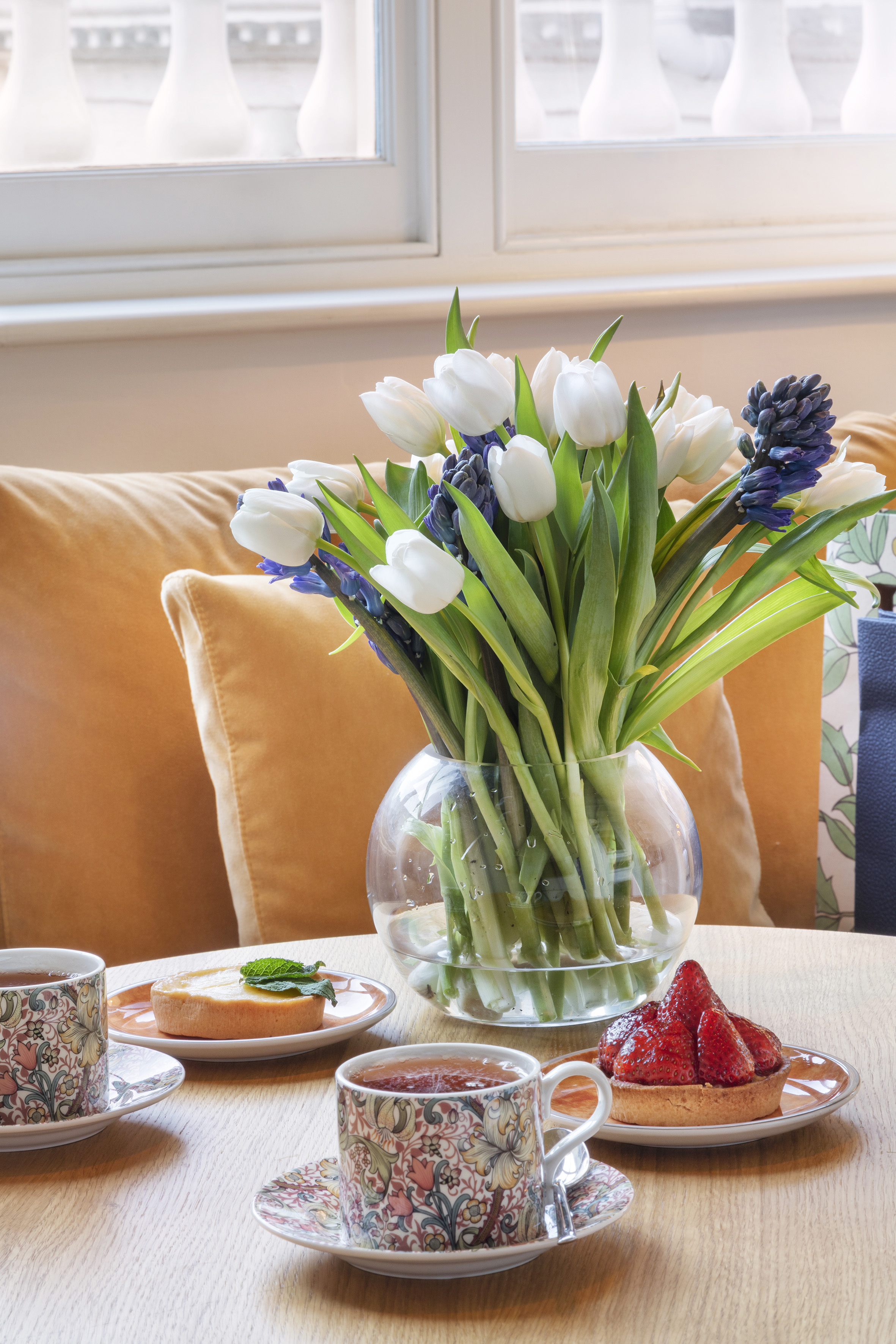 Afternoon tea with fruit tarts, white tulips, and blue hyacinths.