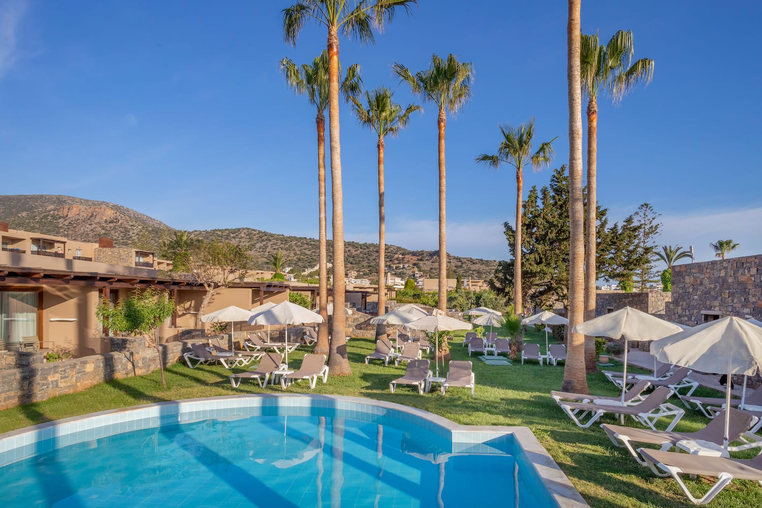 a pool with lounge chairs and umbrellas in a resort