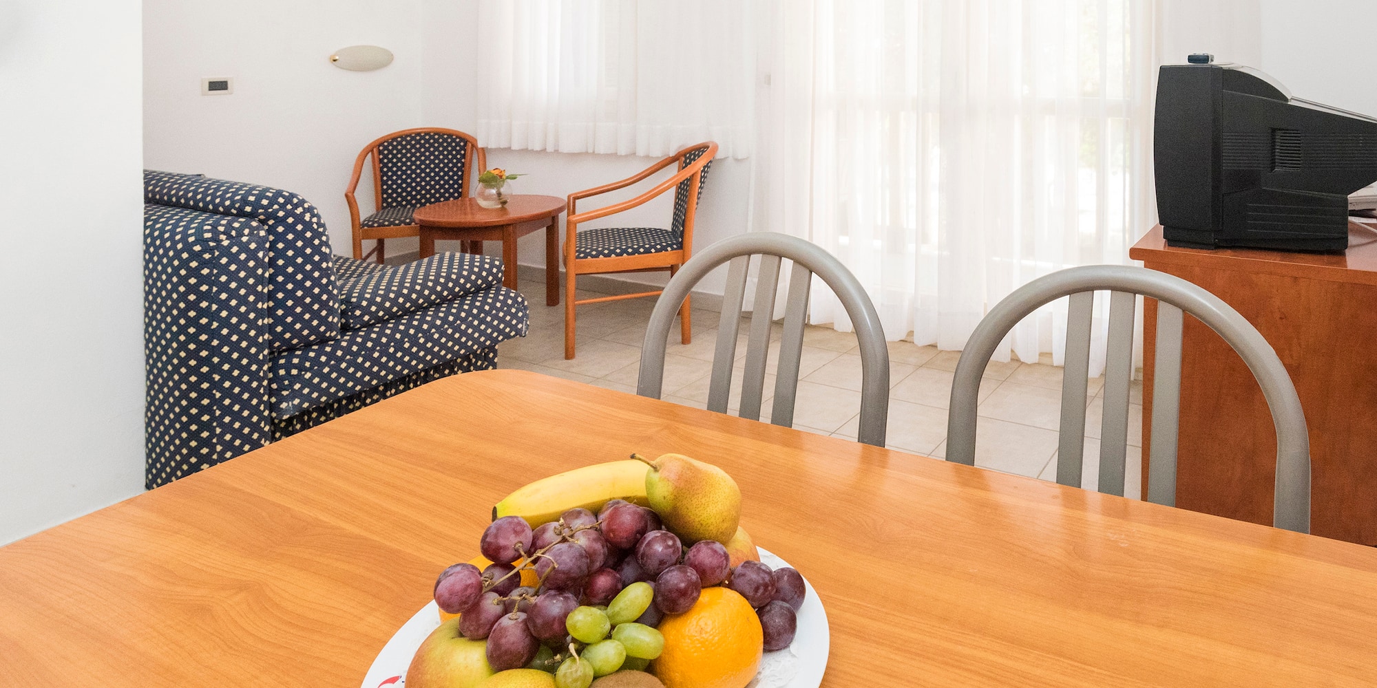 a plate of fruit on a table in a room with chairs and a television