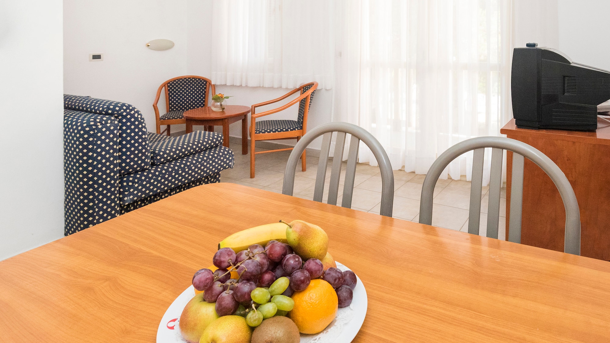 a plate of fruit on a table in a room with chairs and a television