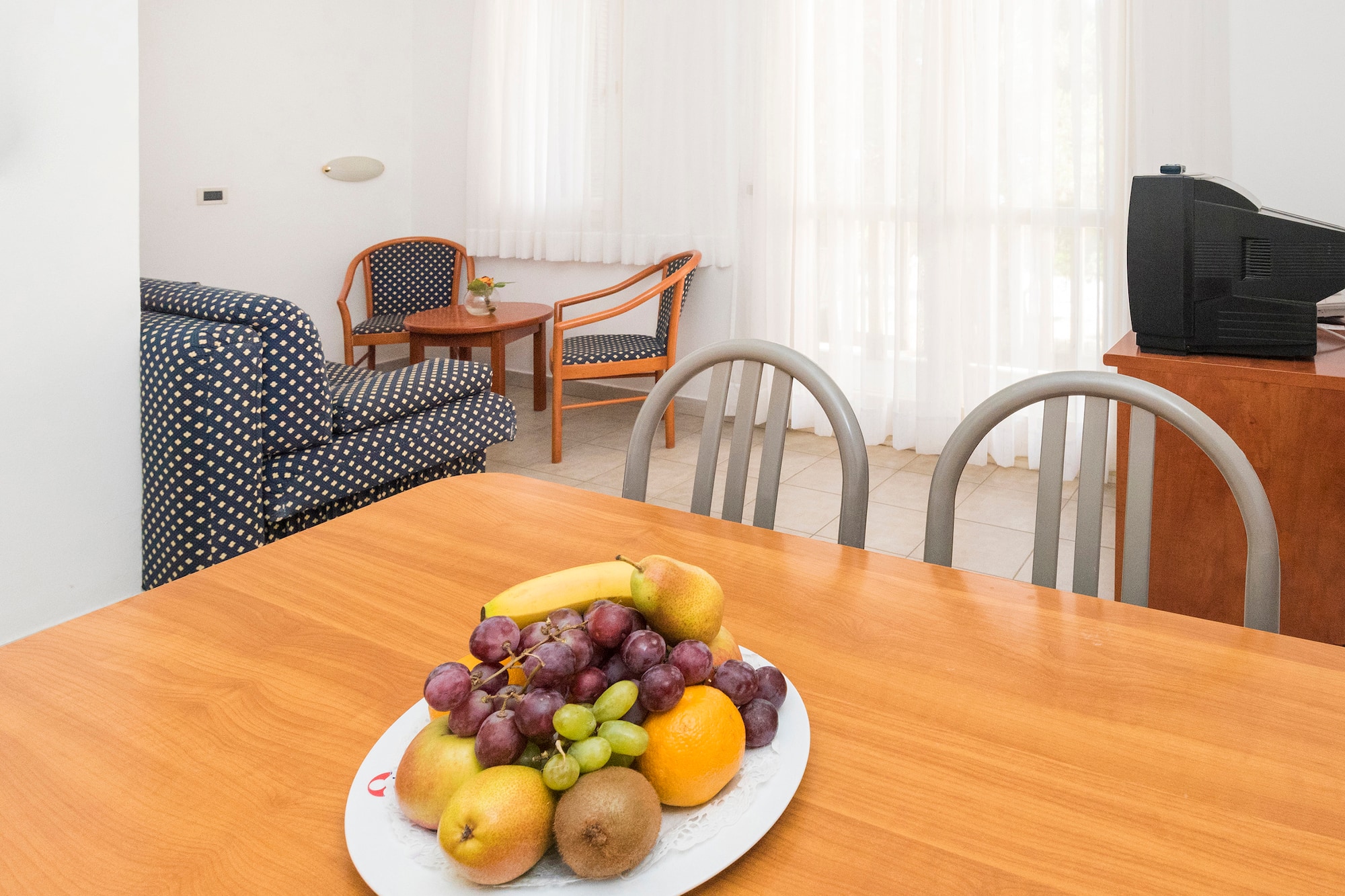 a plate of fruit on a table in a room with chairs and a television