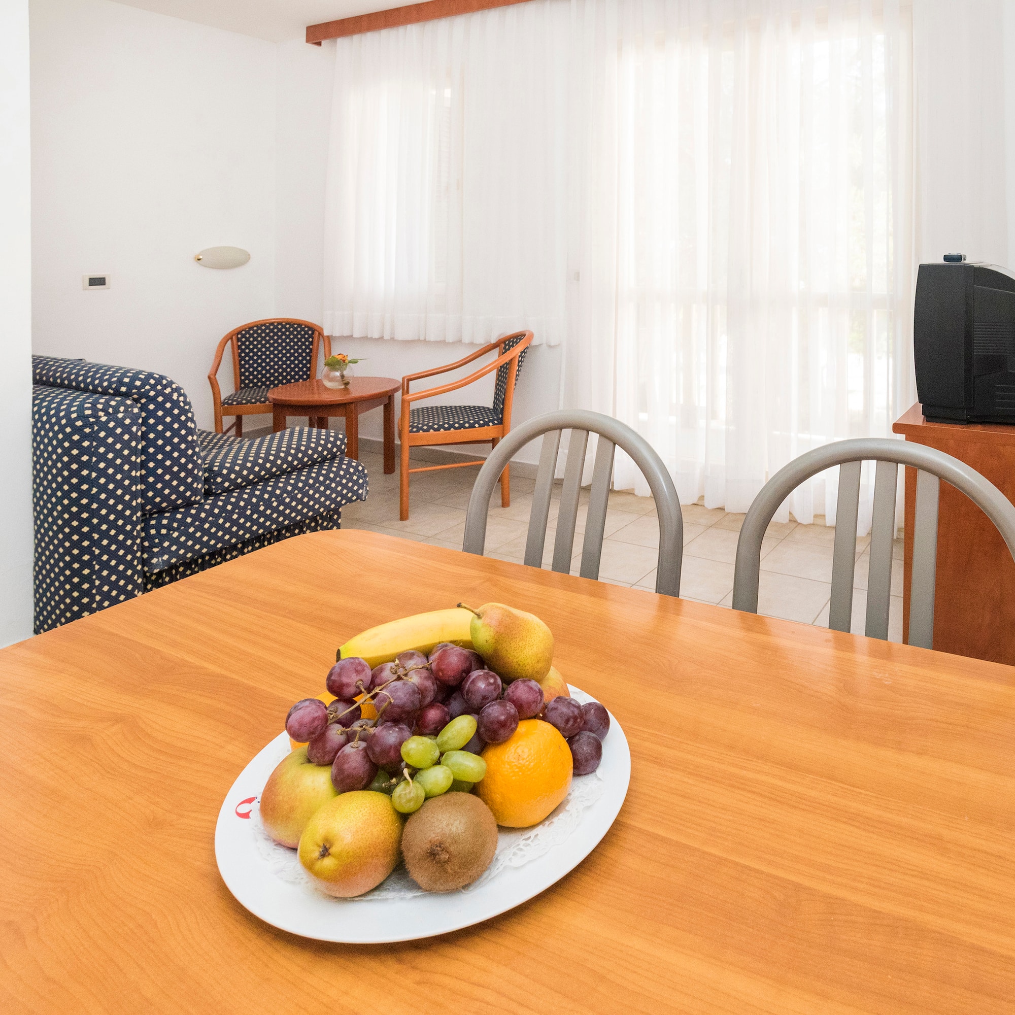 a plate of fruit on a table in a room with chairs and a television