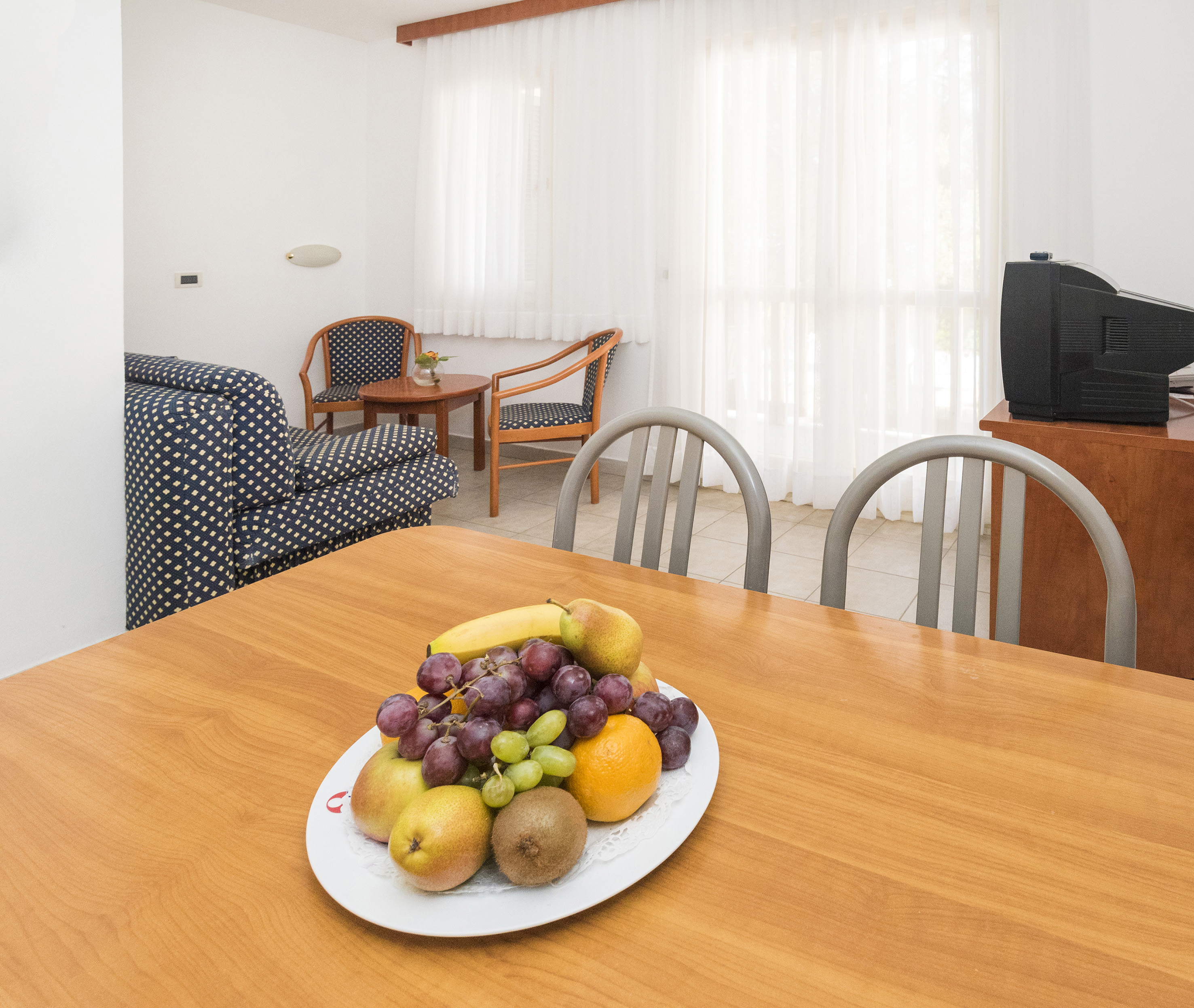 a plate of fruit on a table in a room with chairs and a television