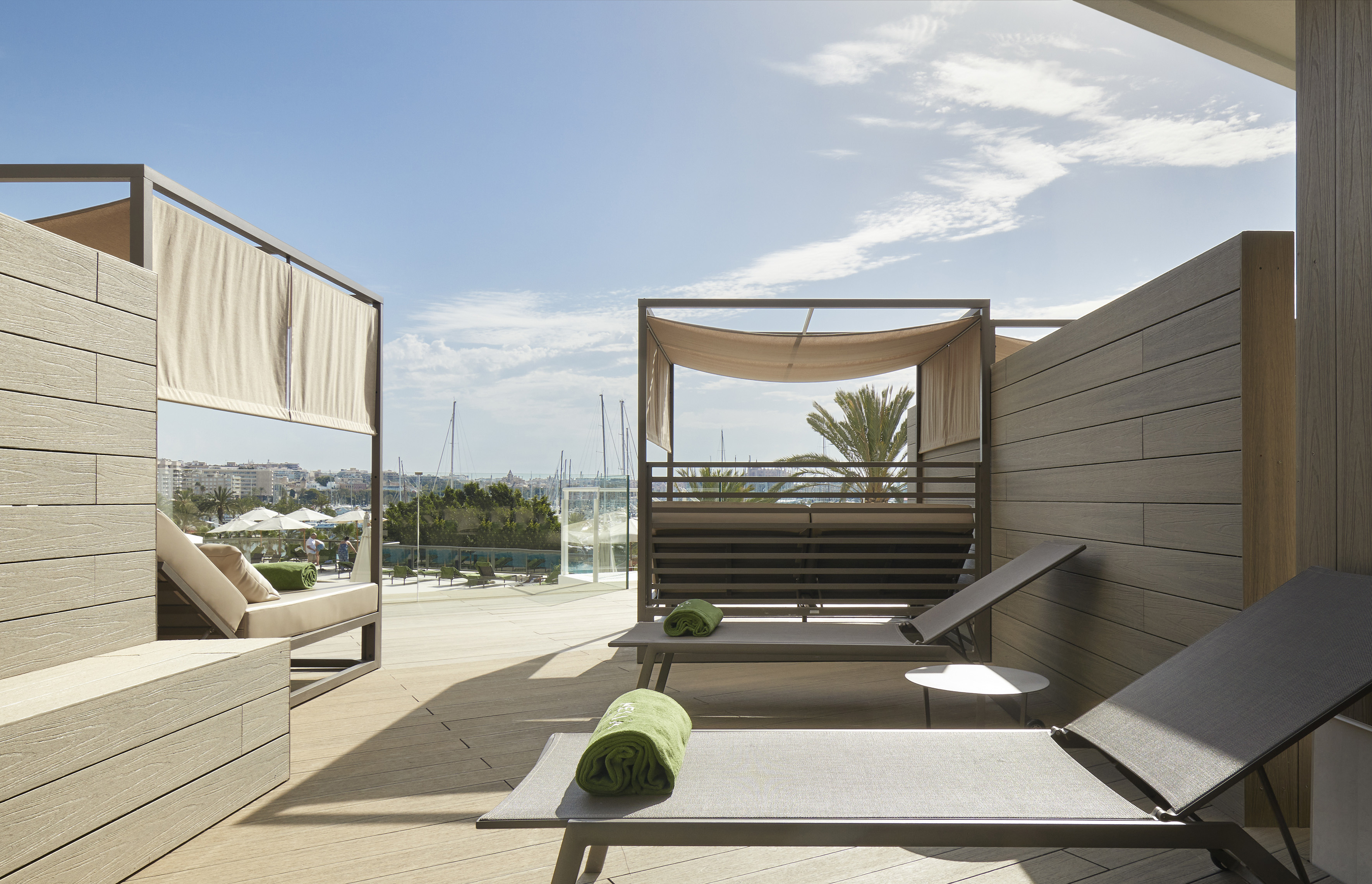 Outdoor lounge terrace with sunbeds, canopies, and marina view.