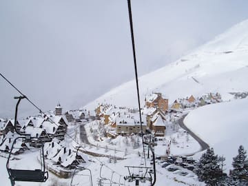 a ski lift with houses and snow on the ground