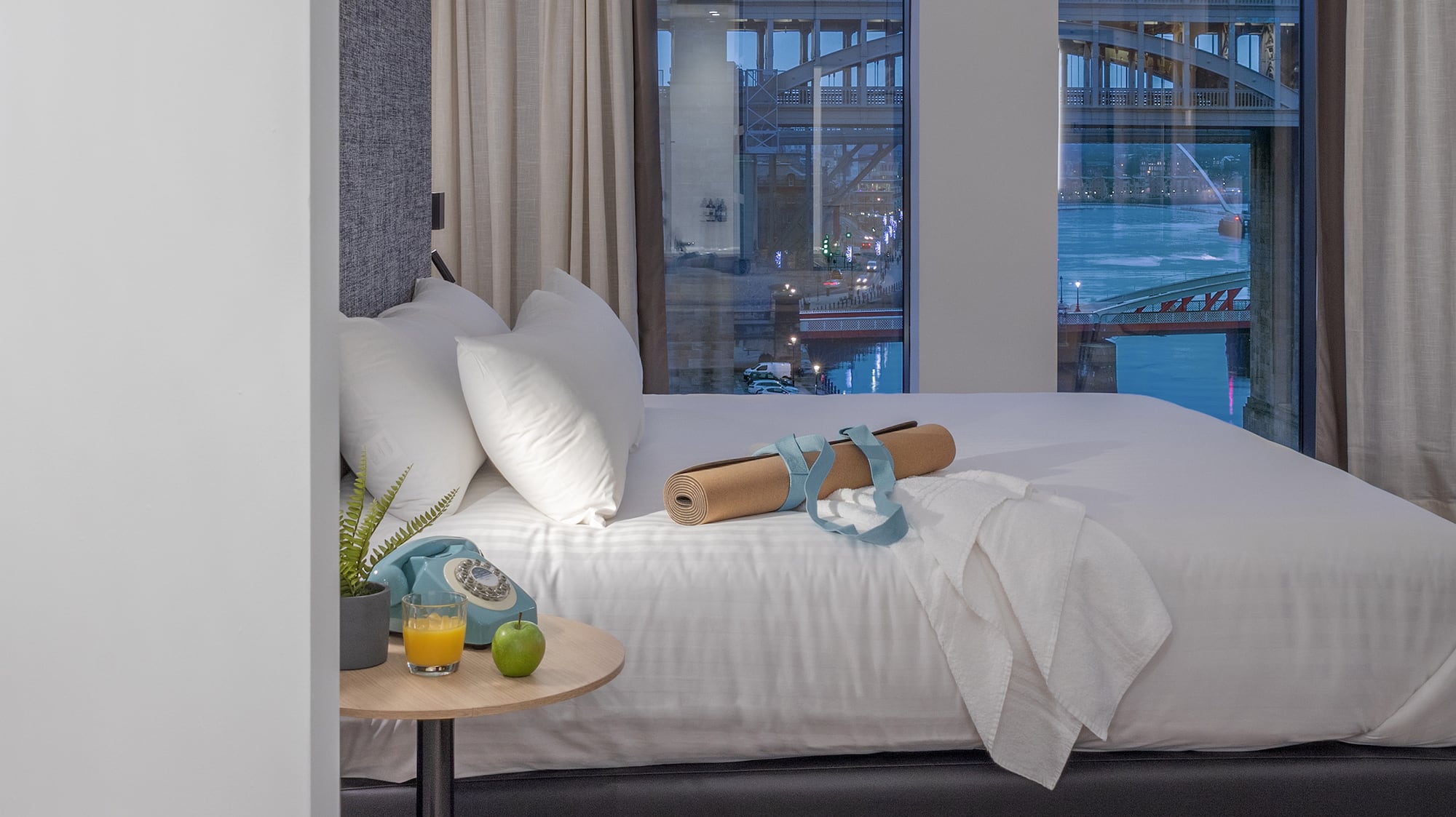 a bed with a table and a table with fruit and a table with a bridge in the background