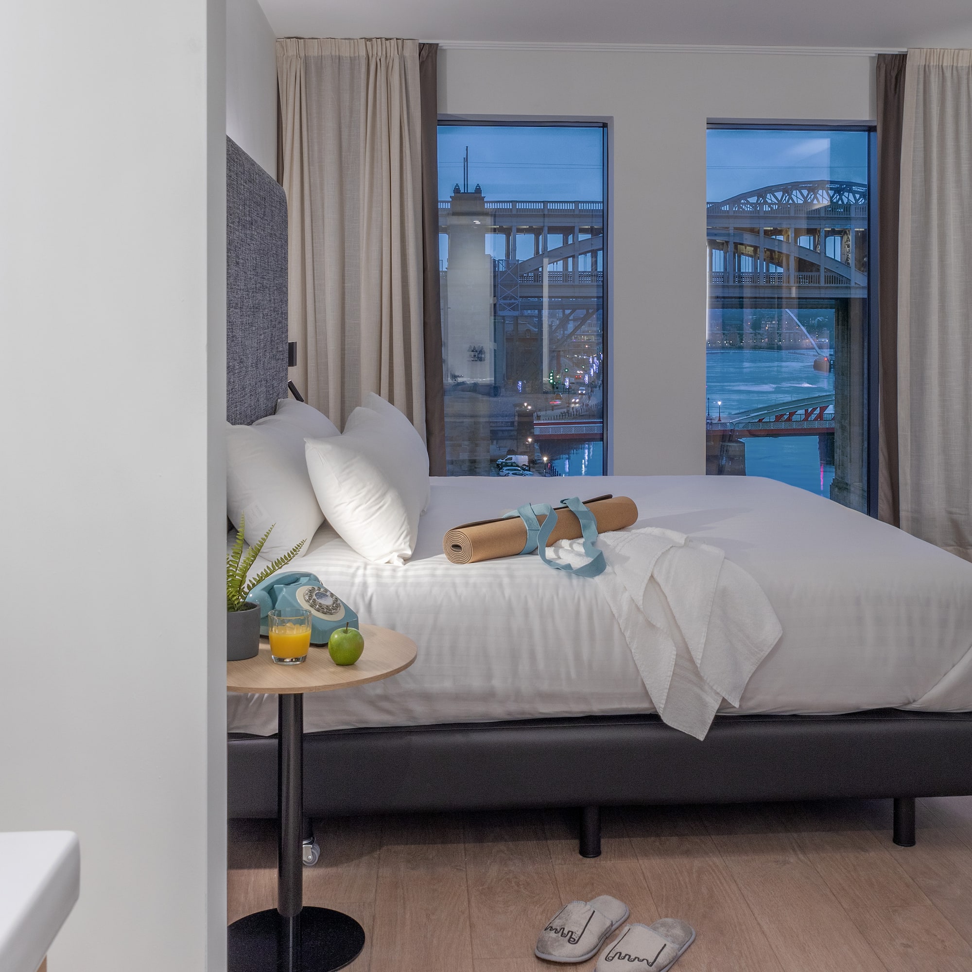 a bed with a table and a table with fruit and a table with a bridge in the background