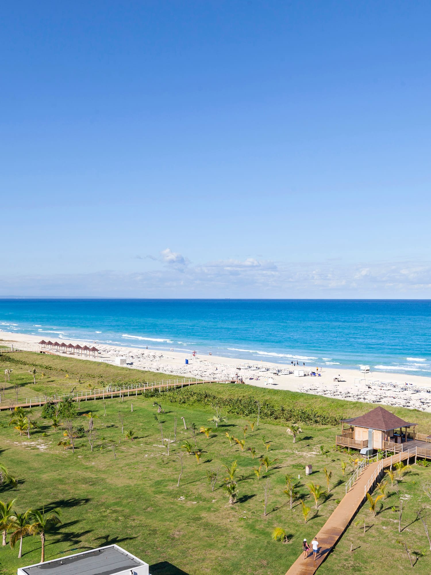 a beach with a green lawn and a walkway