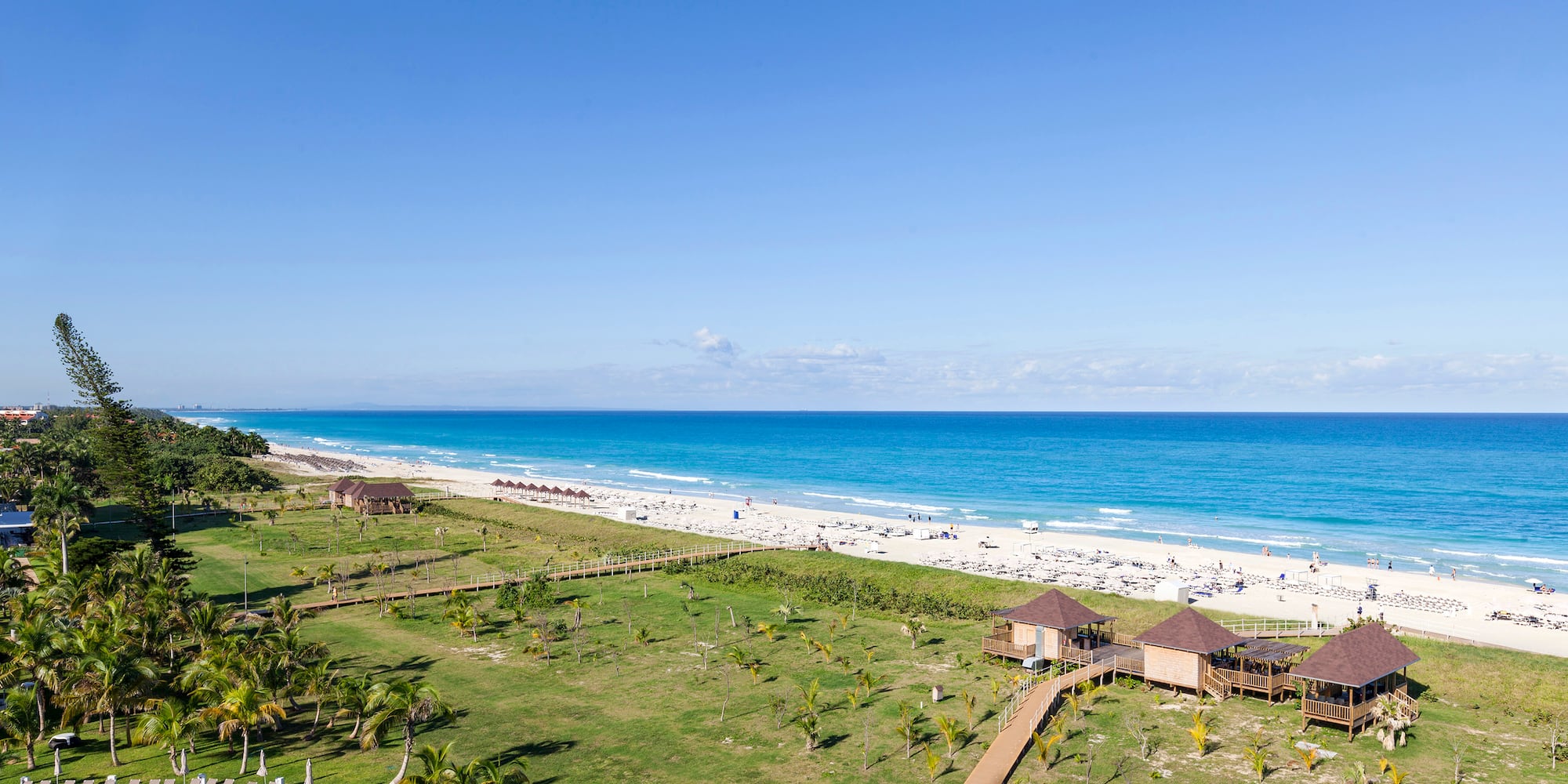 a beach with a green lawn and a walkway