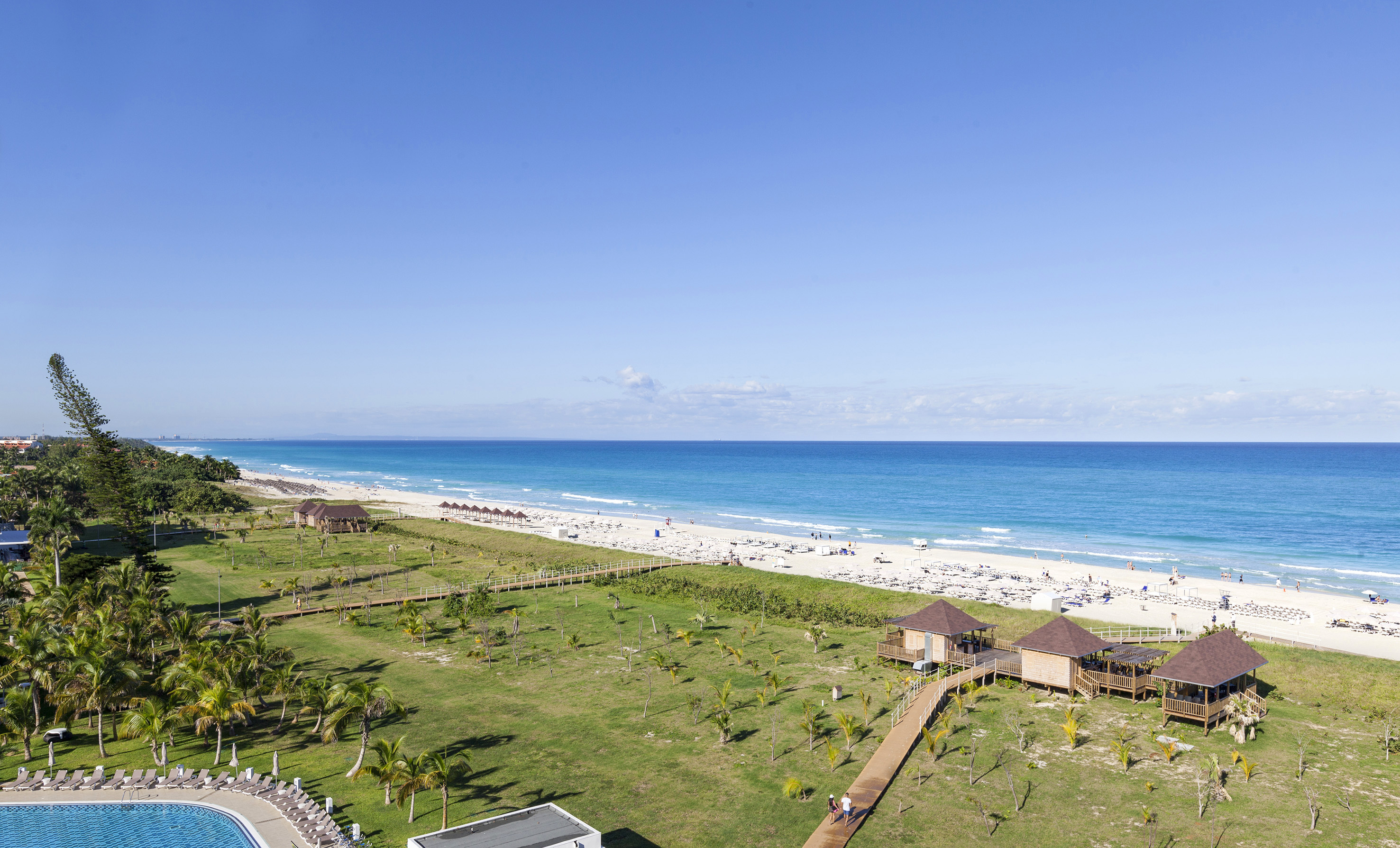 a beach with a green lawn and a walkway