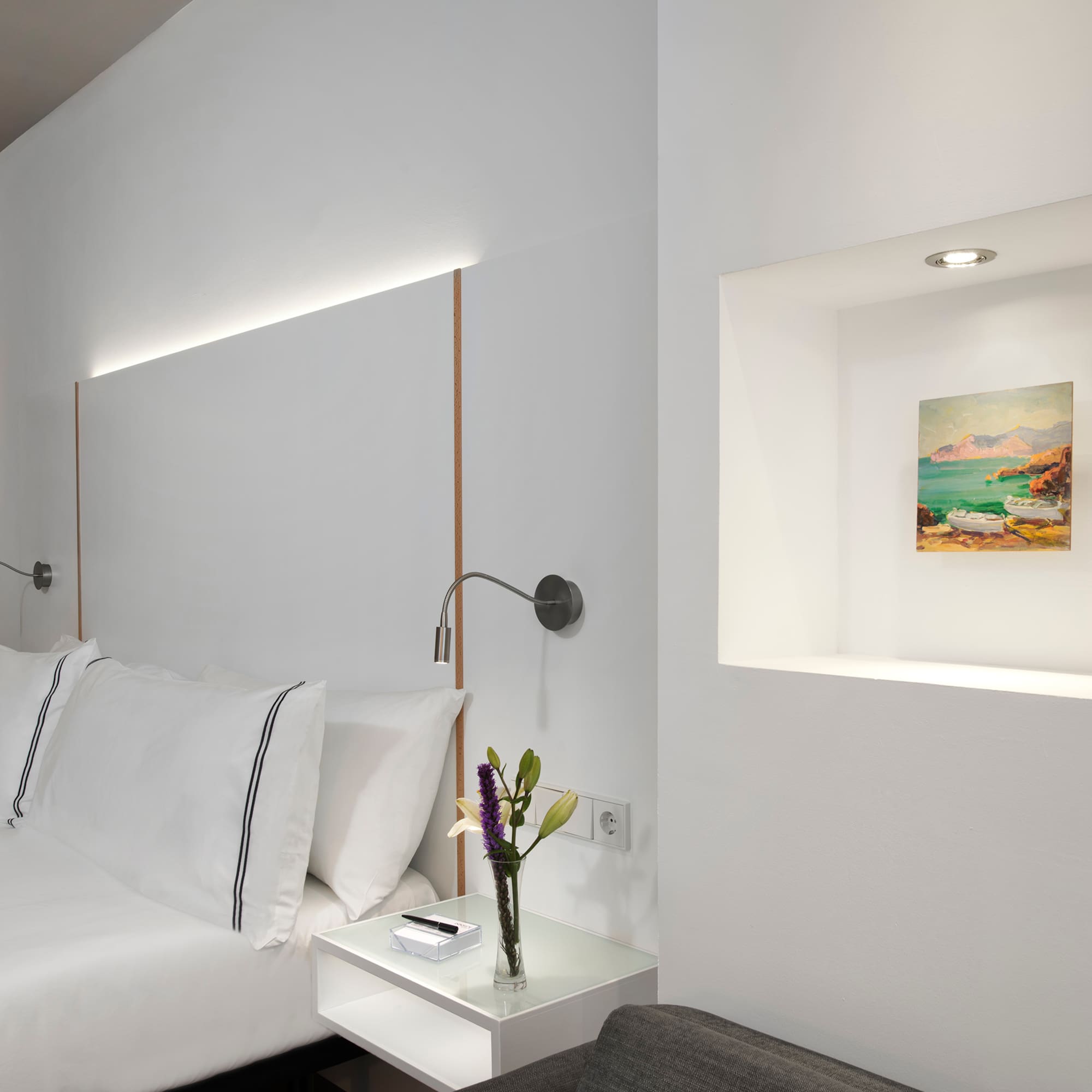 a bed with pillows and a vase of flowers on a table