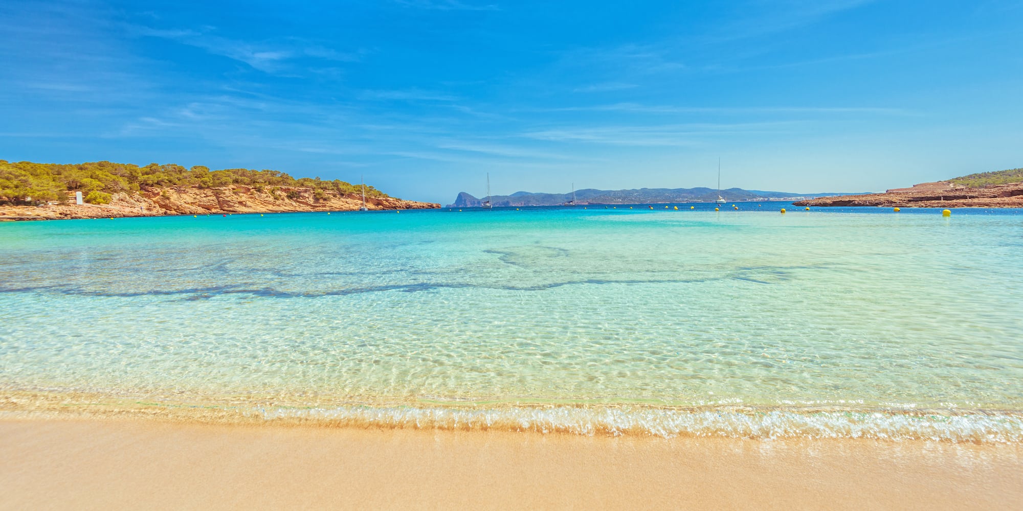 a beach with clear water and blue sky