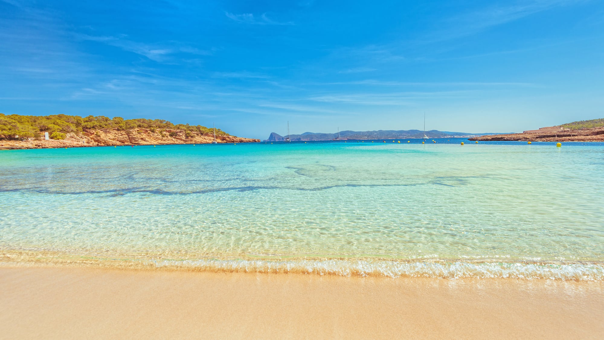 a beach with clear water and blue sky