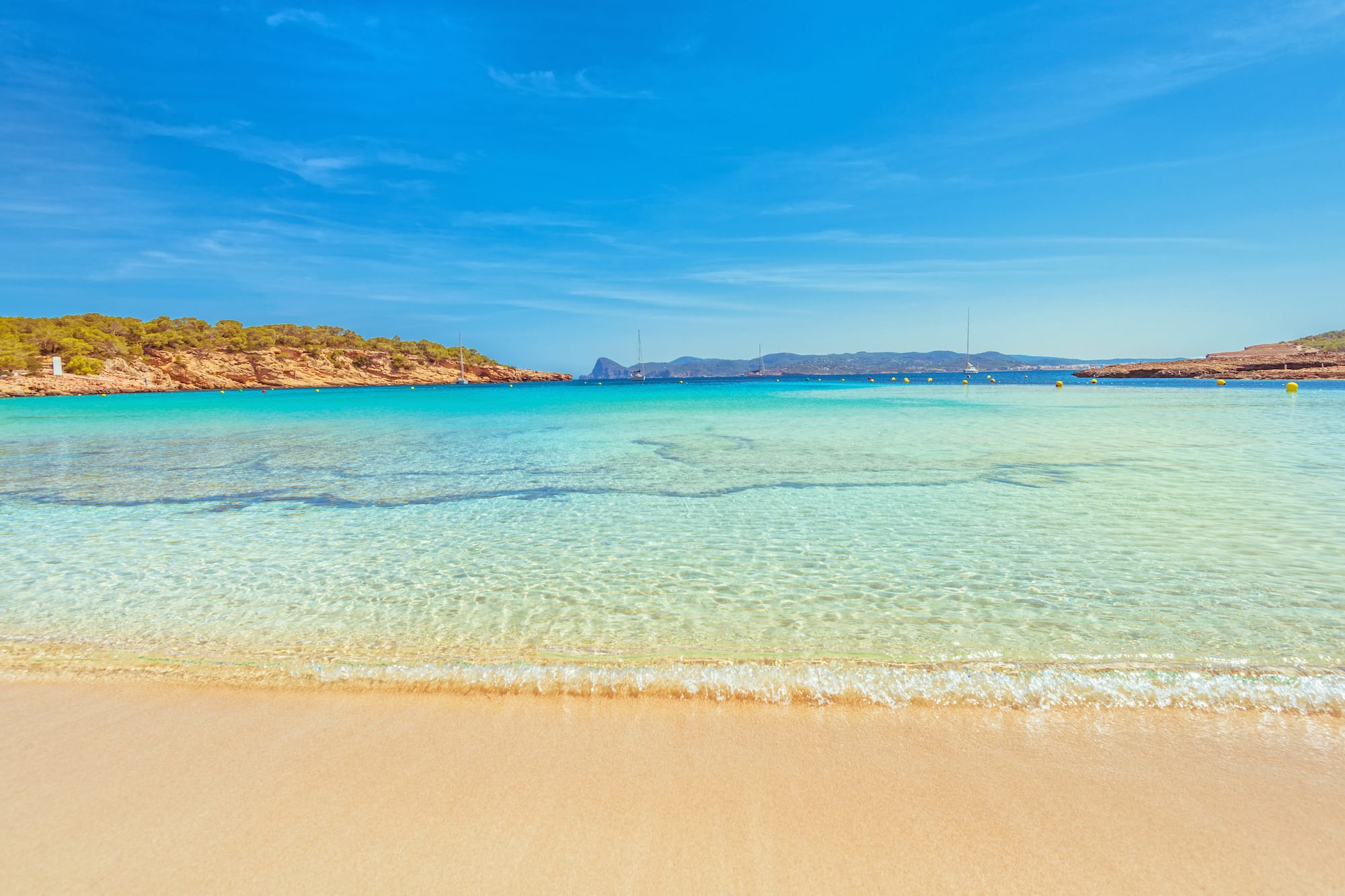 a beach with clear water and blue sky
