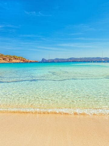 a beach with clear water and blue sky