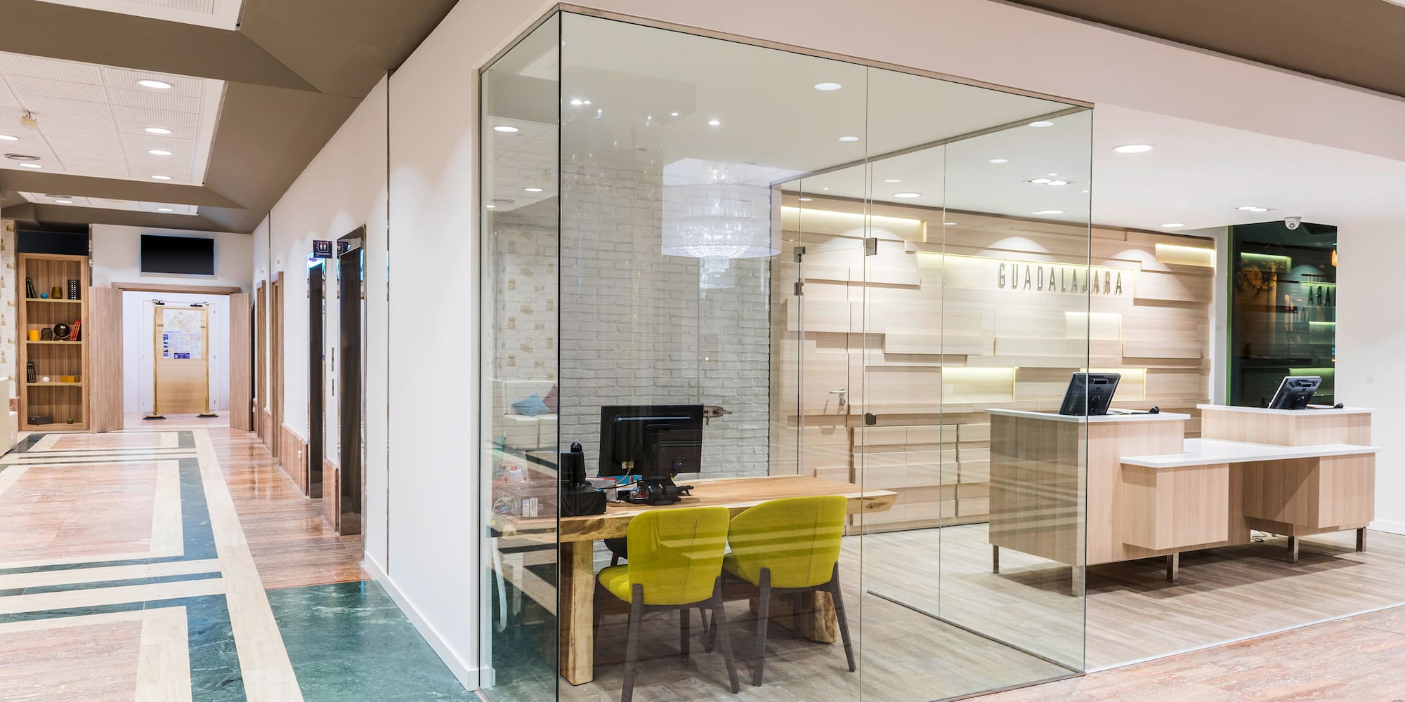 a glass wall with a desk and chairs in it