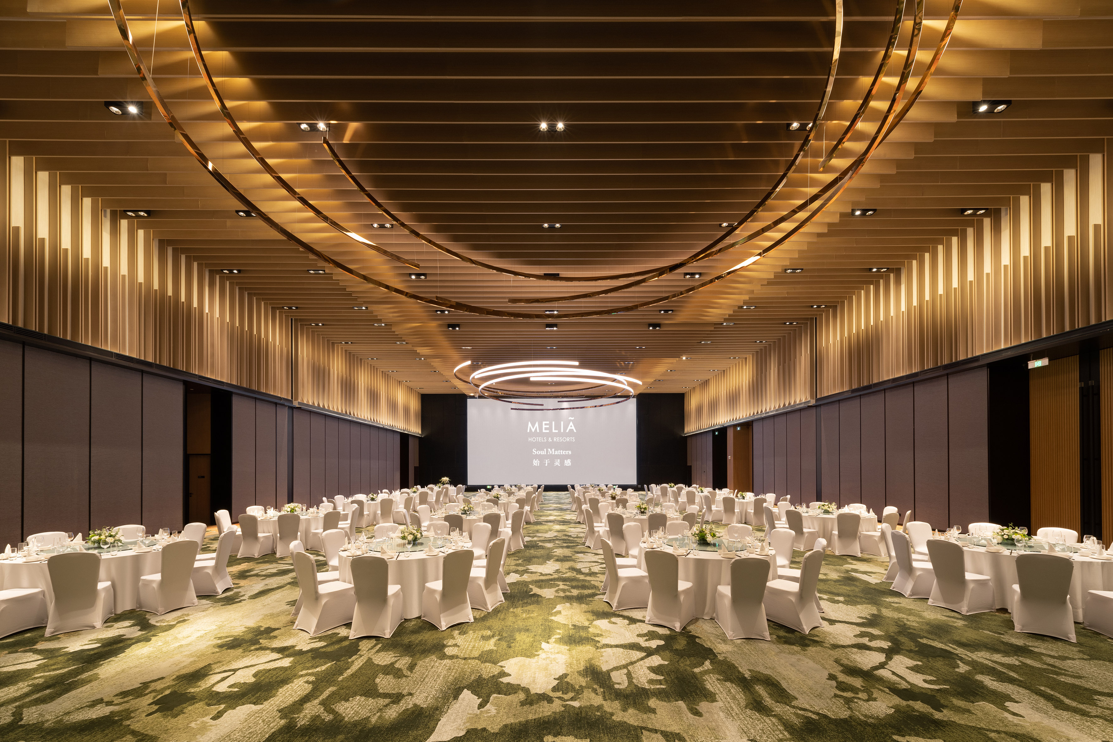 Meliá Hotels & Resorts ballroom with banquet tables, modern decor, and screen.