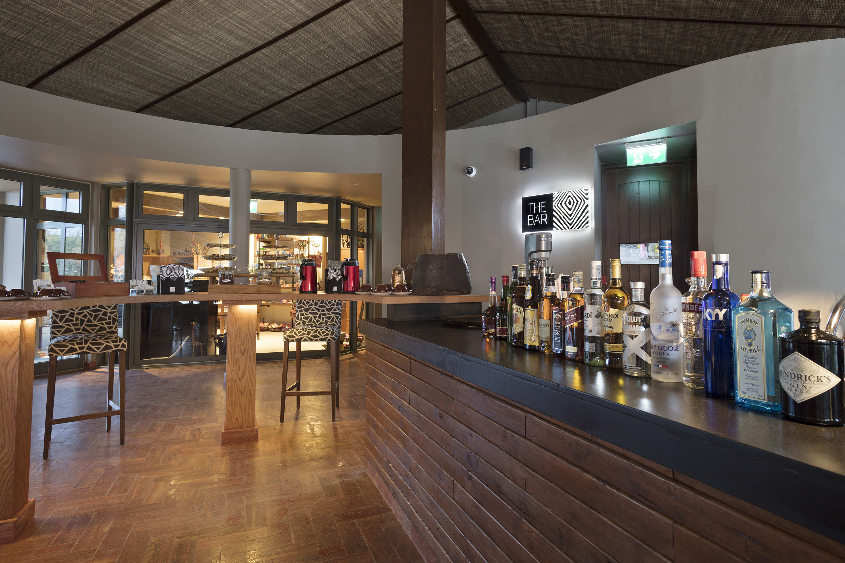 Stylish bar interior with liquor bottles on wooden counter, "THE BAR" sign.