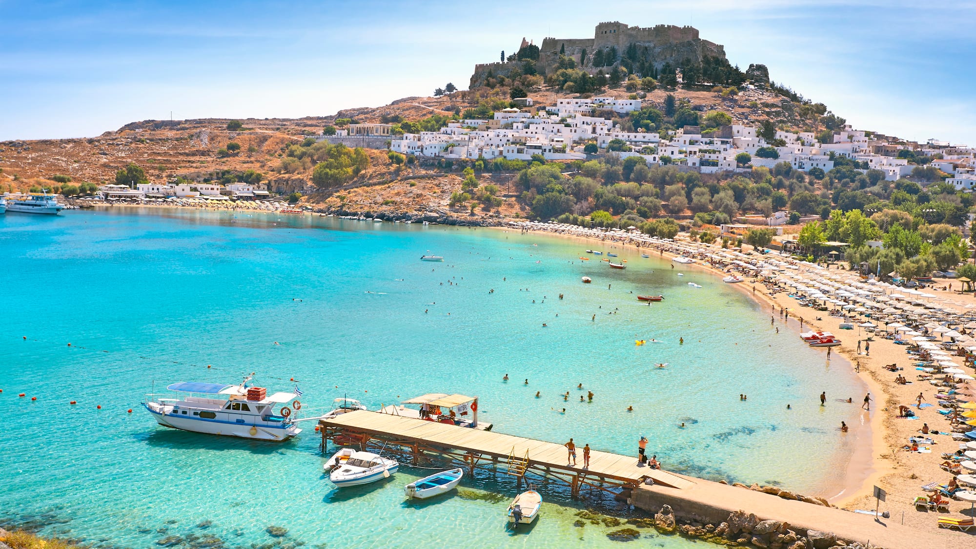 a beach with boats and buildings on the hill