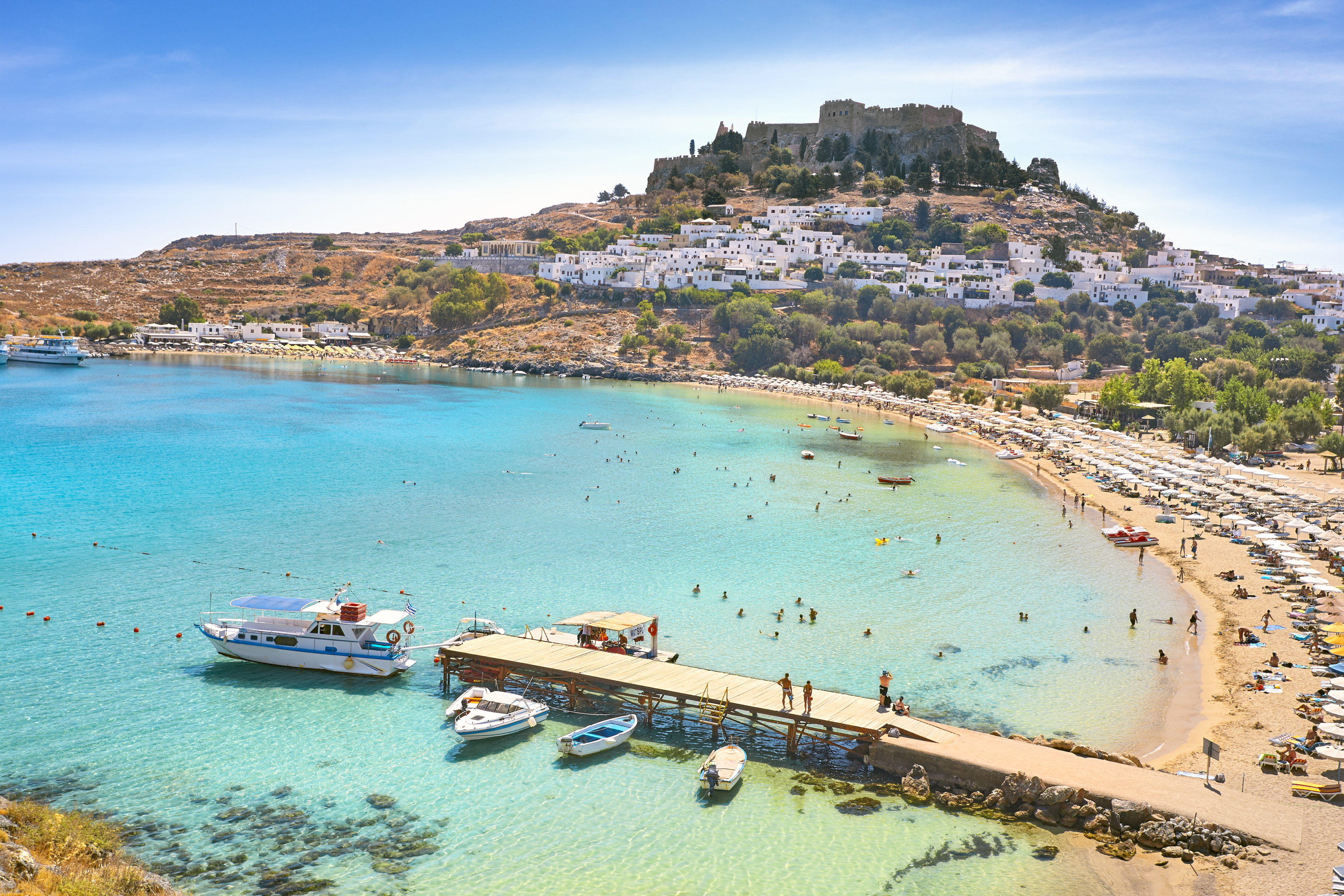a beach with boats and buildings on the hill