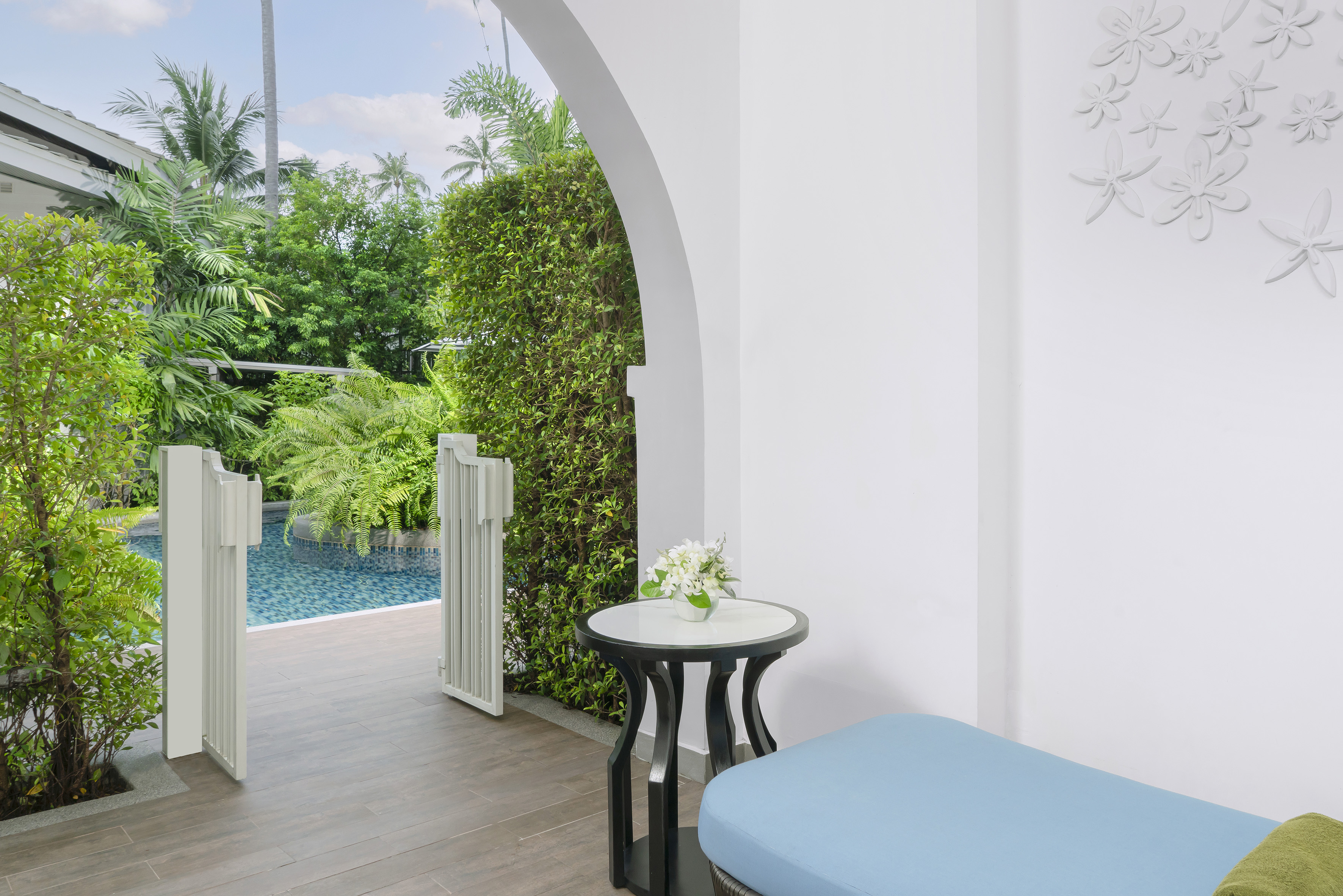 Resort patio with pool access, tropical garden, white archway, and lounge.