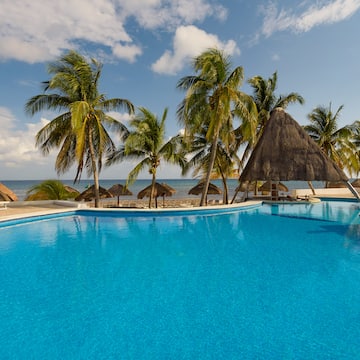 a pool with palm trees and straw umbrellas