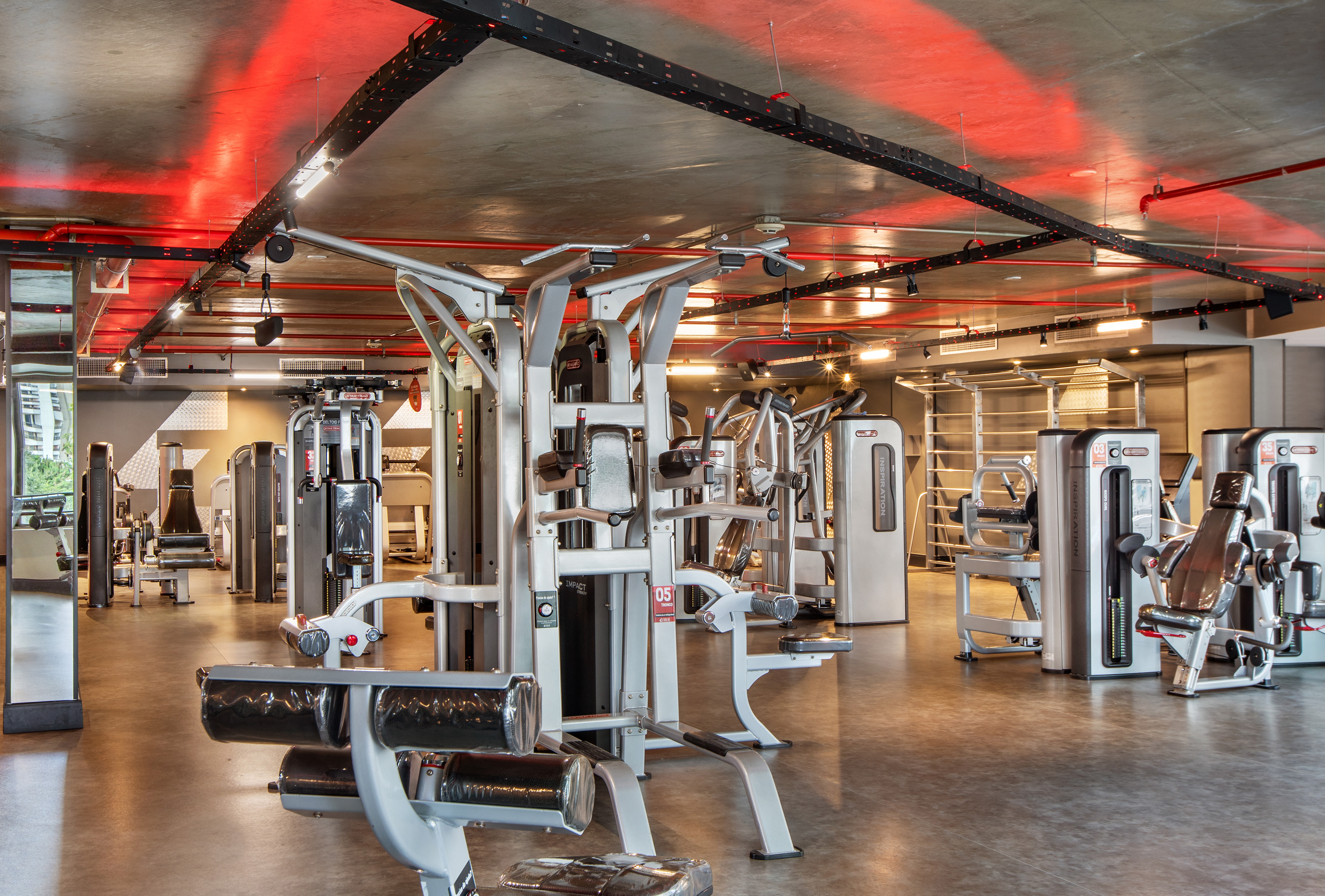 Spacious modern gym with fitness equipment and red accent lighting.