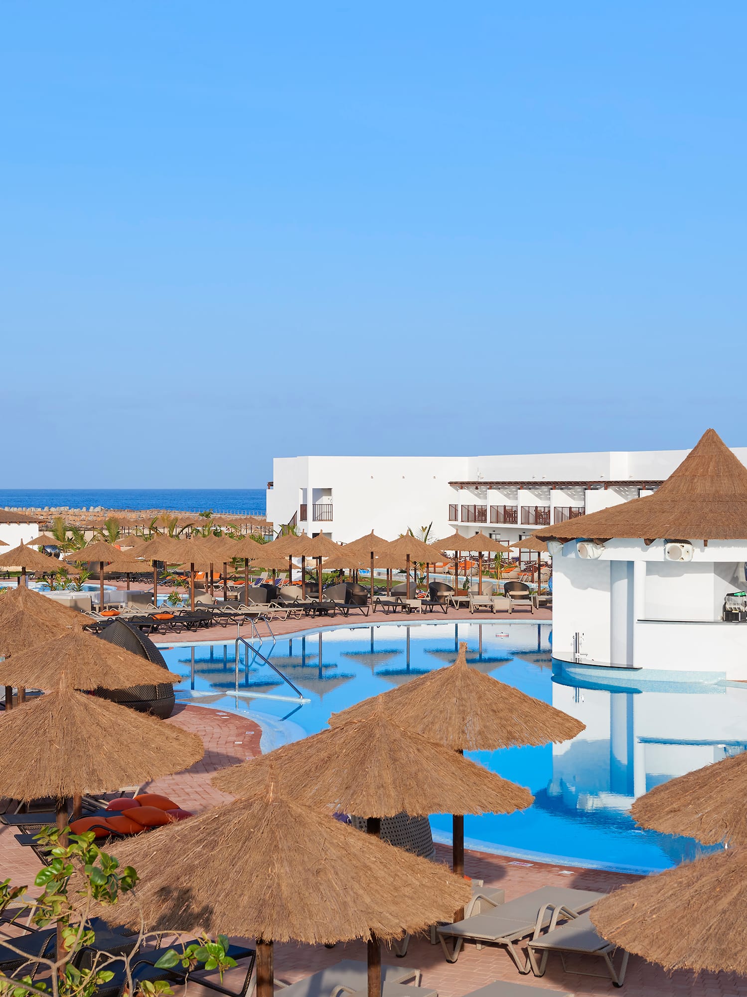 a pool with straw umbrellas and chairs