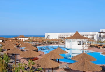 a pool with straw umbrellas and chairs