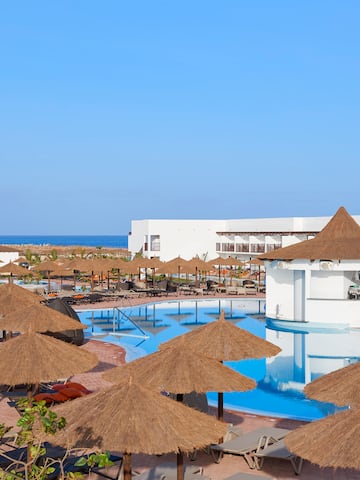 a pool with straw umbrellas and chairs